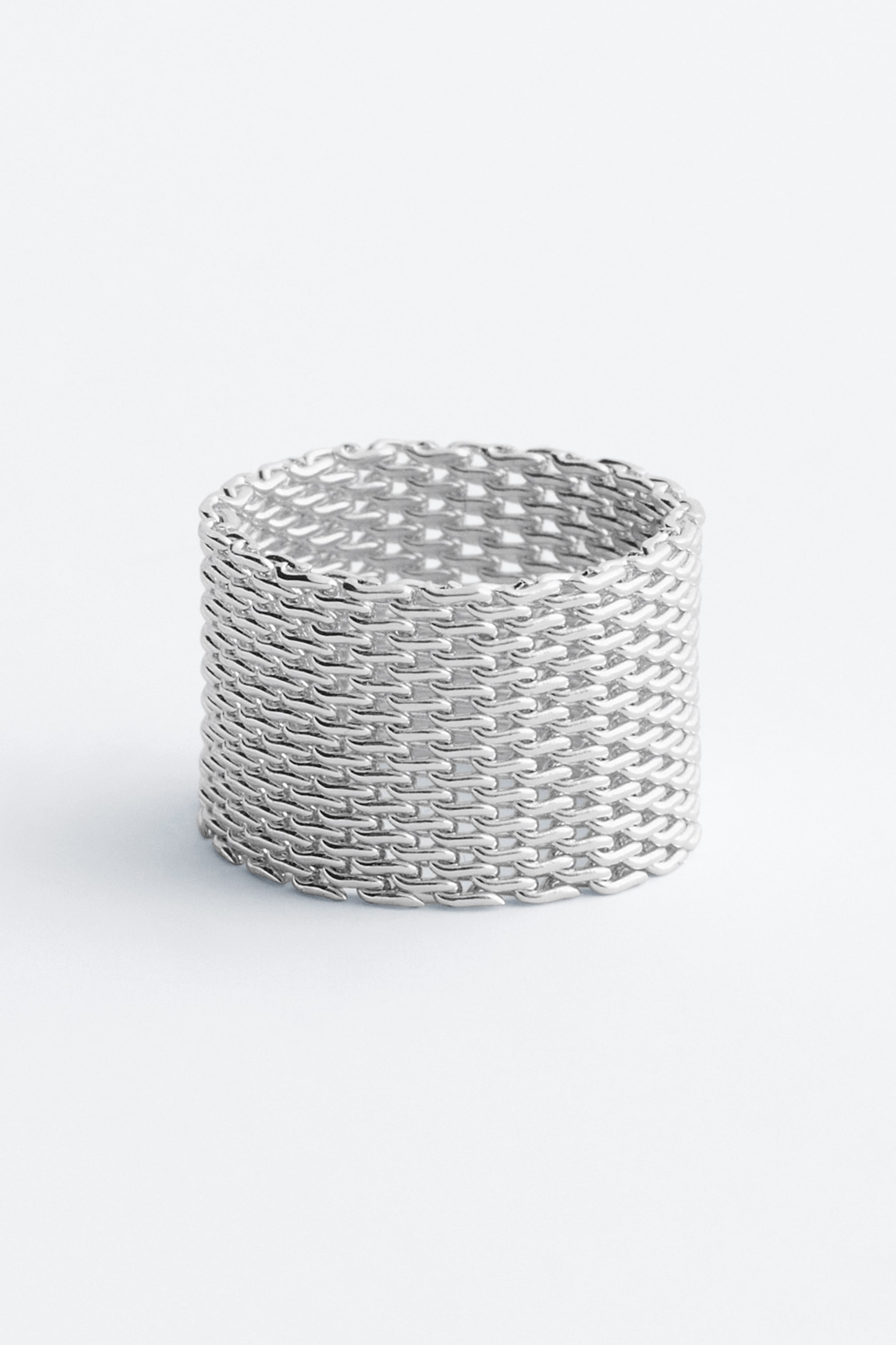 View larger image: A silver-toned ring features a wide, cylindrical band, presenting an intricate mesh design of interlocking links.