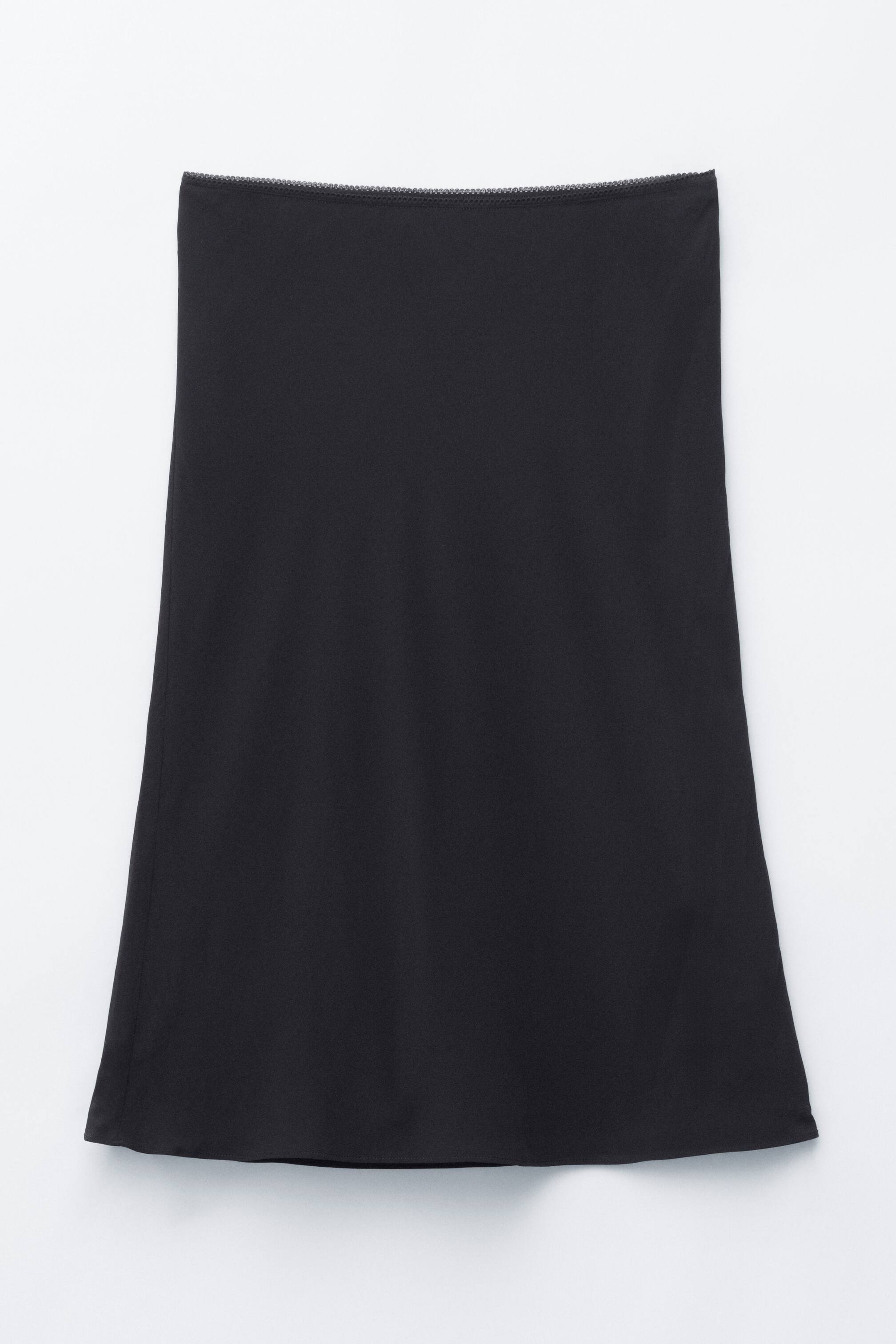 הצגת תמונה גדולה יותר: חצאית סליפ שחורה מוצגת שטוחה מהחזית, עם סילואט ישרה שמתפשטת בעדינות לכיוון השוליים, ומותן אלסטי עם גימור מסולסל.