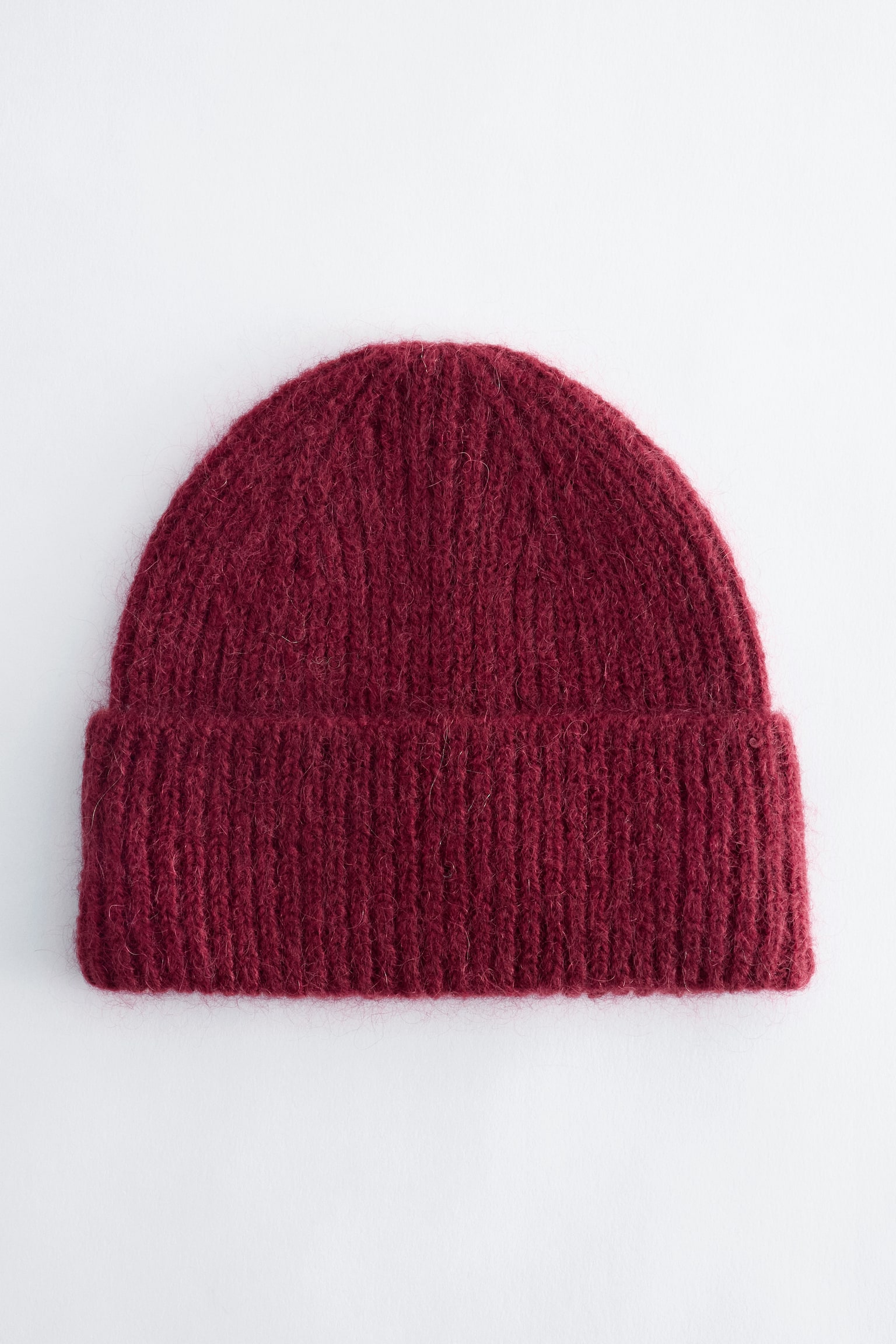 Um gorro canelado cor borgonha Ã© apresentado de frente, com uma textura fofa em mistura de mohair e uma aba larga dobrada.