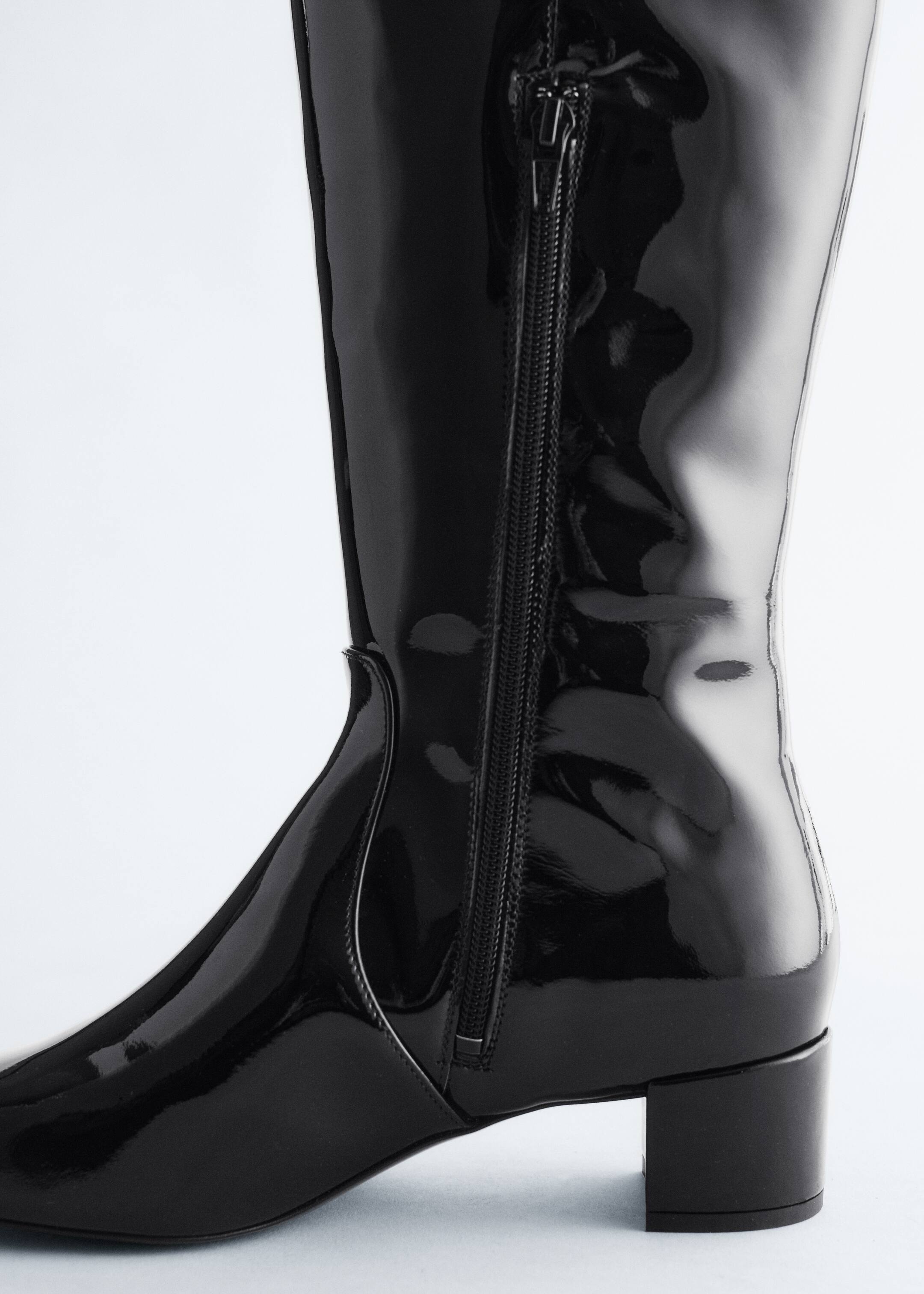 Agrandir l'image: Une botte en cuir verni noir est inclinée vers la DROITE, avec une tige ajustée dotée d'une fermeture éclair latérale sur toute la longueur et un talon bloc bas.