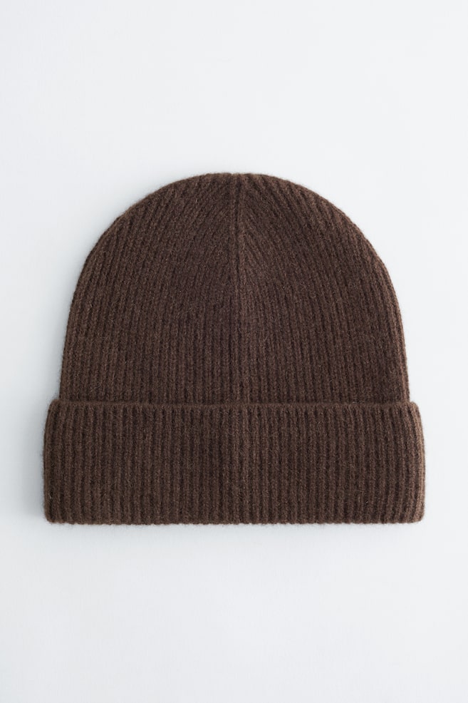Un bonnet en cachemire marron foncé est présenté de FACE, avec une texture en maille côtelée sur toute la surface et un large revers côtelé. - 1
