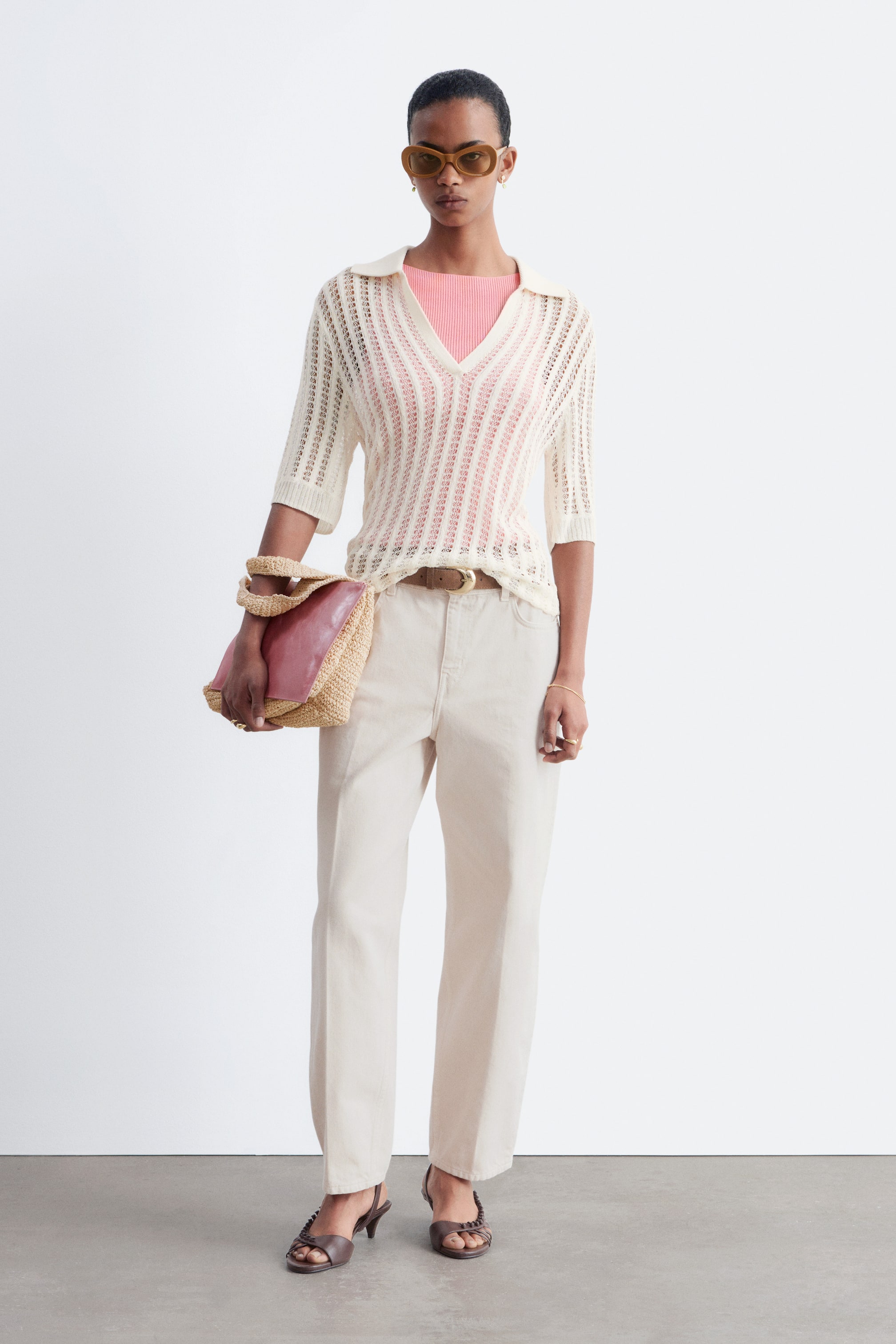 Visualizza l'immagine ingrandita: Jeans beige chiaro a 5 tasche con vita regolare e gambe affusolate indossati dalla modella. I jeans presentano pieghe pressate nette e una zip frontale visibile con chiusura a bottone, assicurati con una cintura marrone.