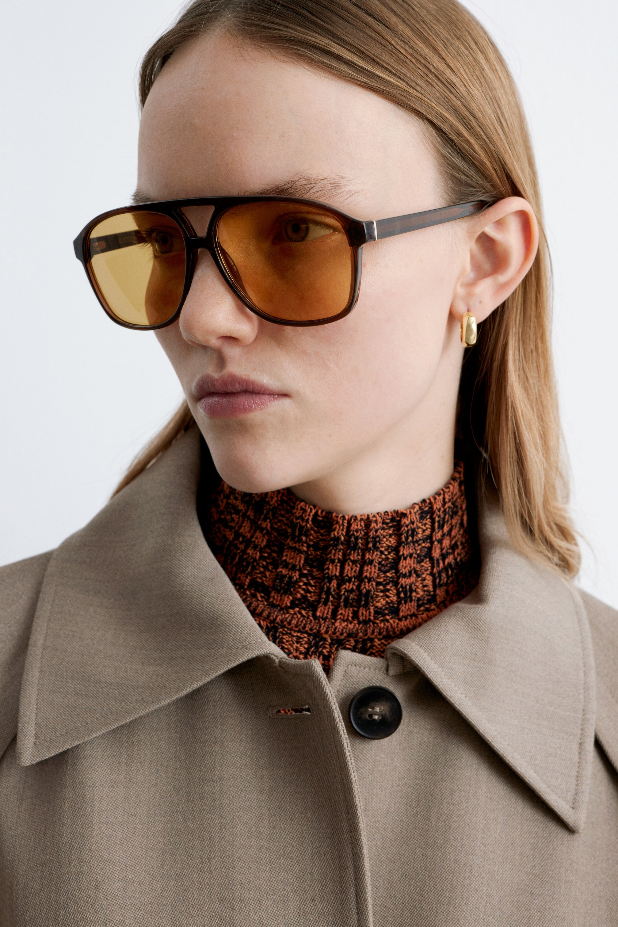 Se større billede: Oversized solbriller i aviator-stil, set forfra, har brune stel med afrundede kanter, en klassisk brynbar og slanke stænger. De er afsluttet med tonede gule linser.