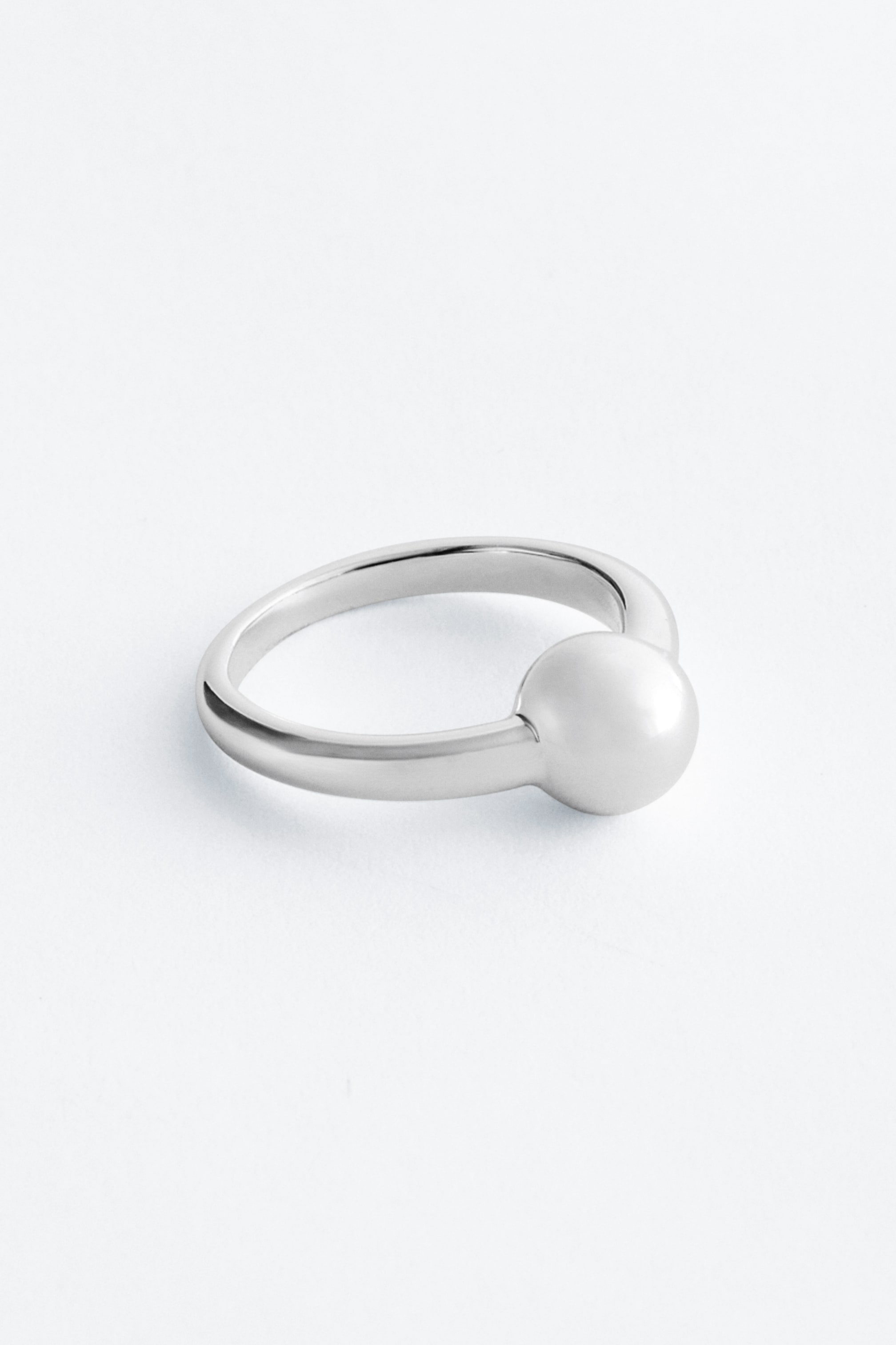 Grotere afbeelding bekijken: Een gepolijste metalen ring met een bolvormig detail geïntegreerd in de band.