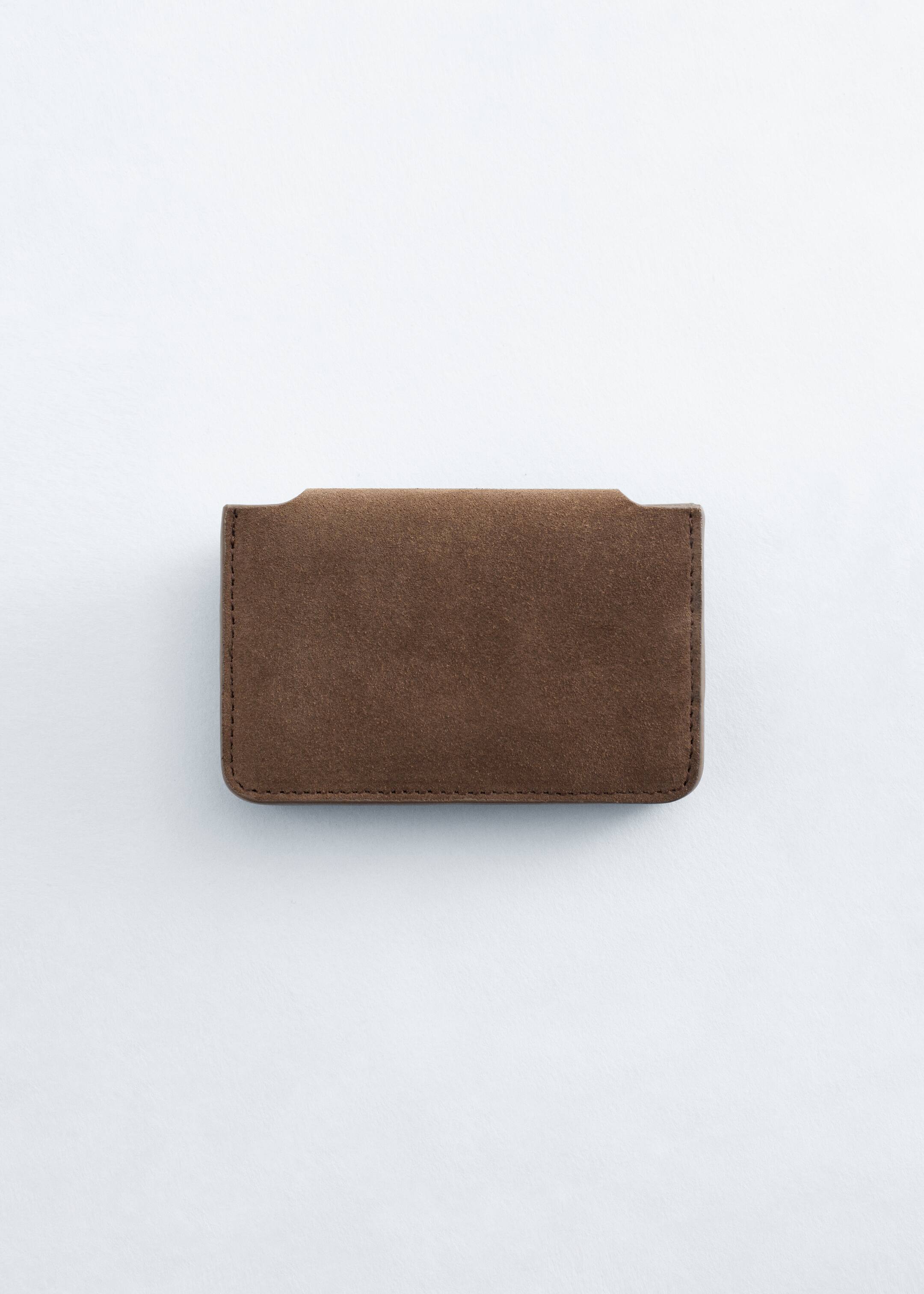 Agrandir l'image: Un porte-cartes rectangulaire en cuir suédé brun est présenté de face, avec des coutures visibles le long de son périmètre et des découpes courbées subtiles sur son bord supérieur.