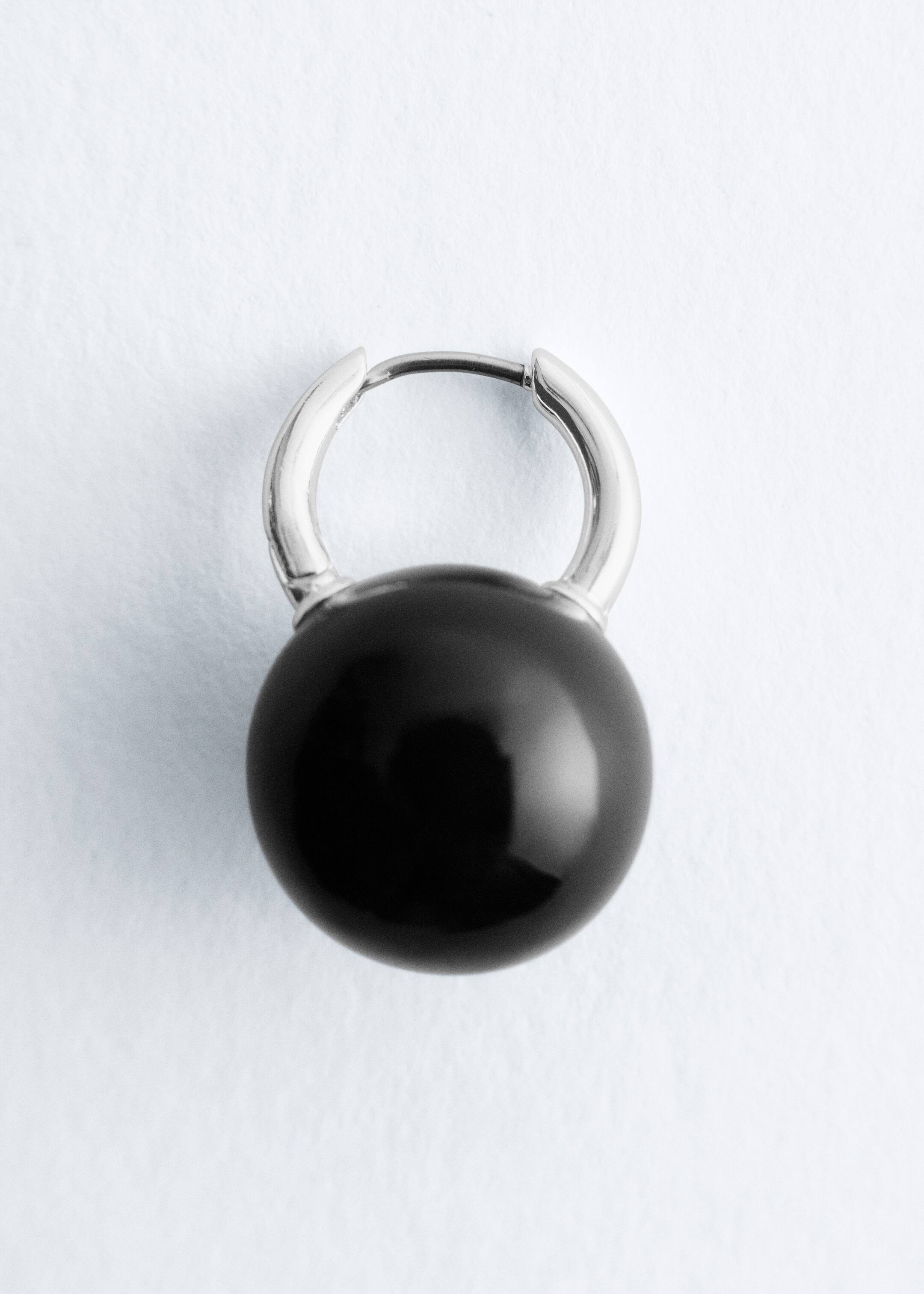 Visa större bild: En enkel polerad mässingsringörhänge presenteras FRAM ifrån och har en gångjärnsförslutning med en stor, blank svart sfärisk pärla som ligger placerad inuti ringen.