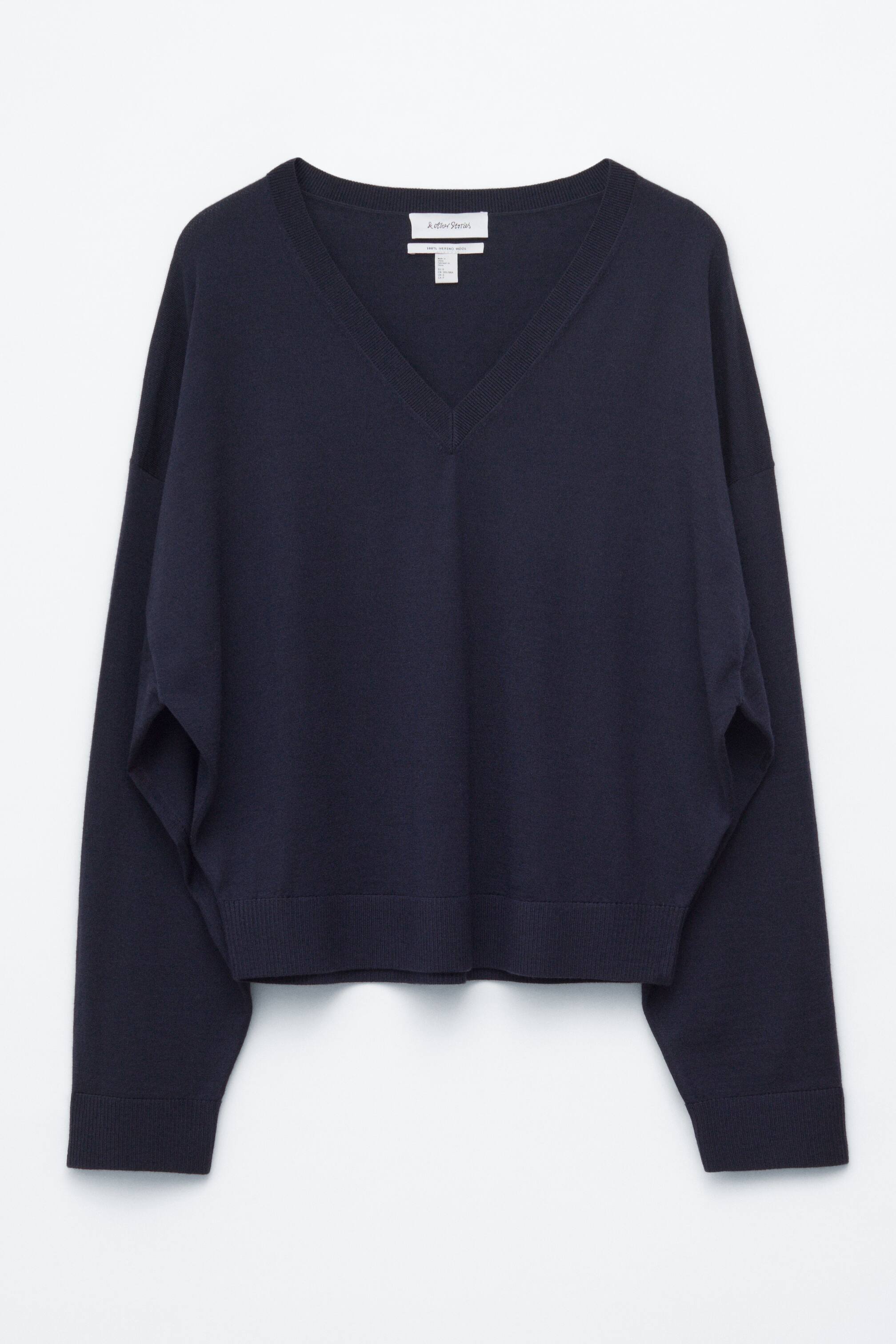Agrandir l'image: Un pull en laine bleu foncé est présenté de face, mettant en valeur une silhouette surdimensionnée et carrée avec des épaules tombantes basses, des manches longues se rétrécissant aux poignets côtelés, un profond décolleté en V avec bordure côtelée, et un ourlet côtelé.