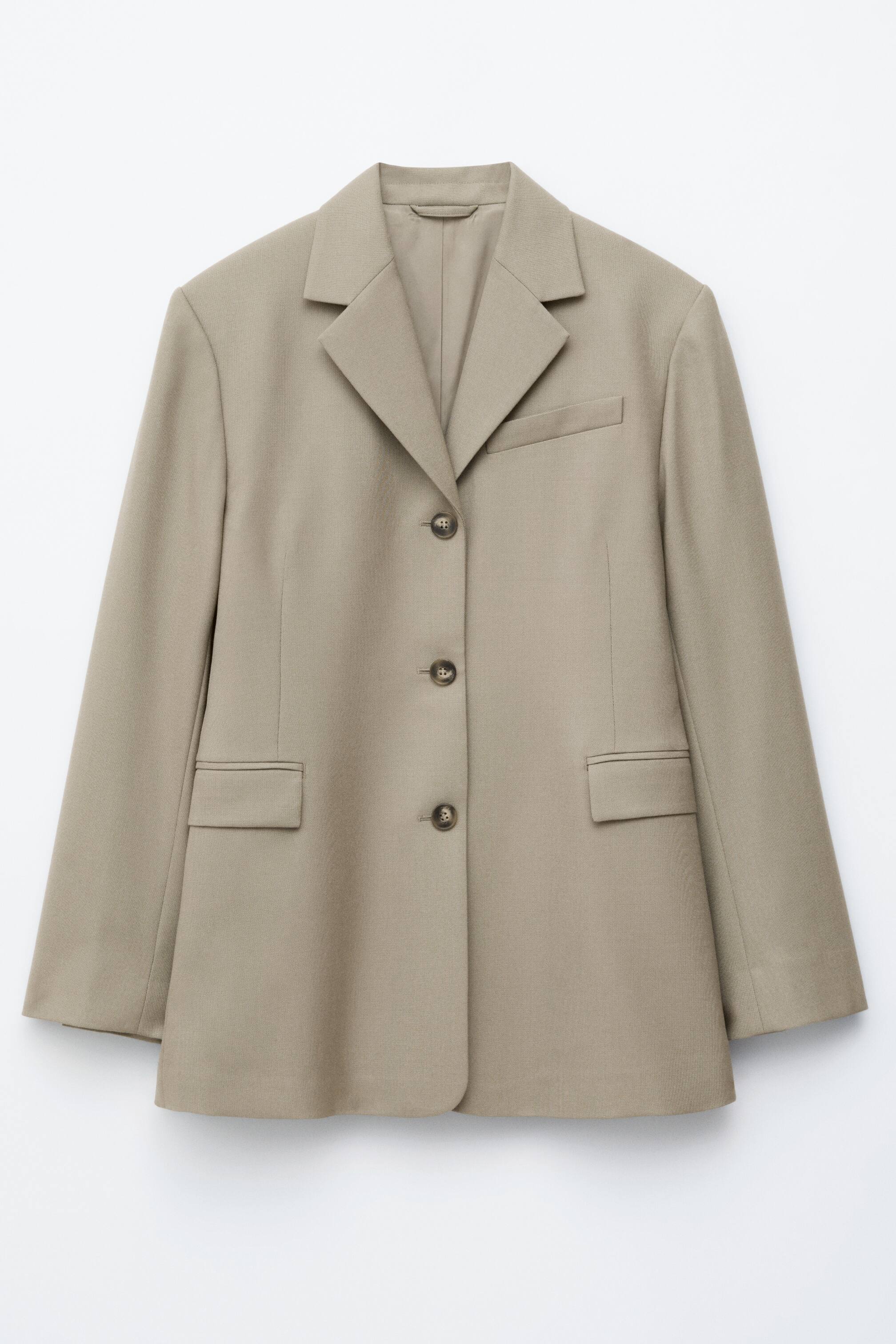Vis større bilde: En lys brun blazer vises, vendt MOT FORAN. Den har hakkeslag, lange ermer, en treknapps frontlukking med mørkebrune knapper, en enkelt brystlomme med passepoil på venstre side, og to klaffelommer ved hoftene.