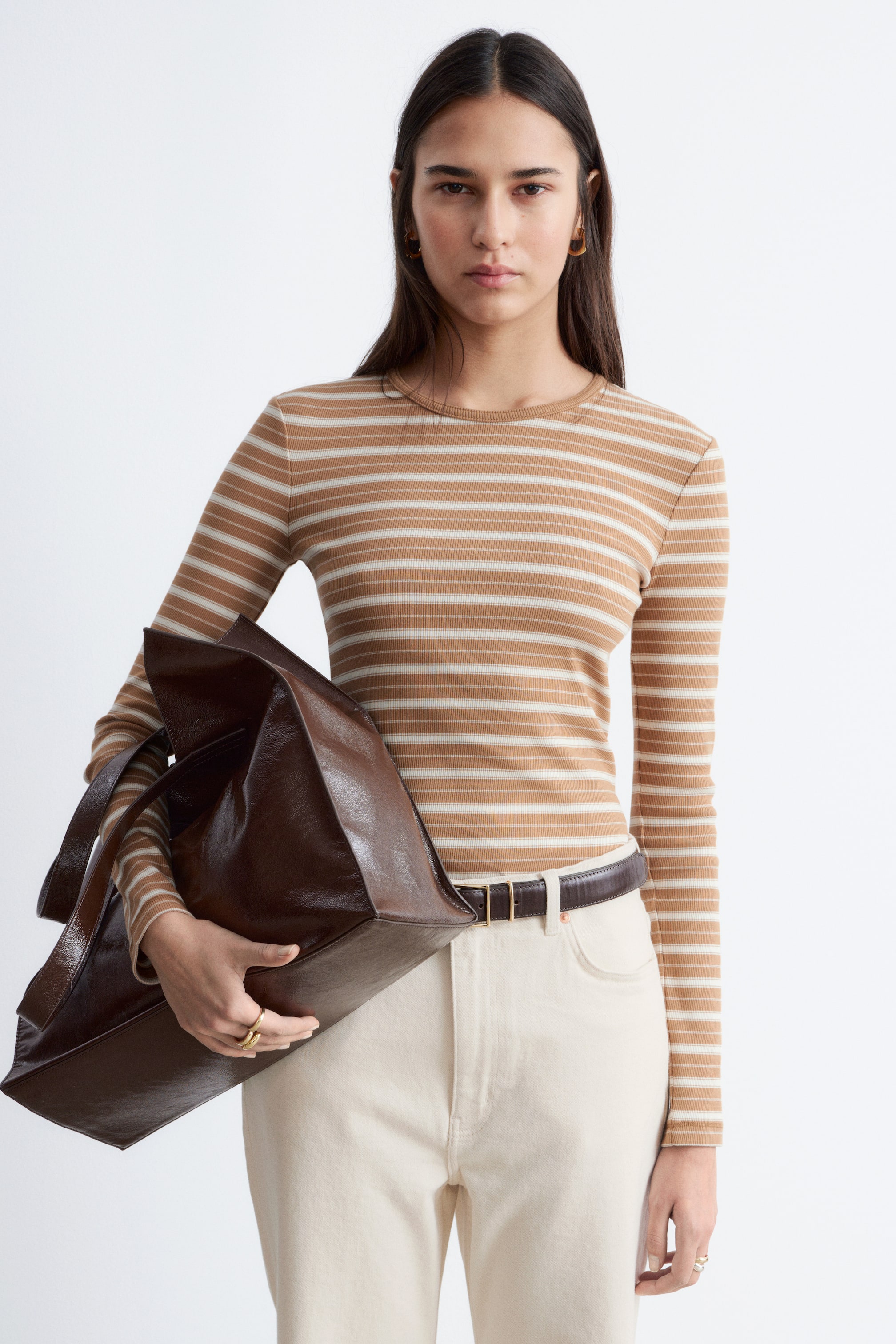 הצגת תמונה גדולה יותר: חולצה עם שרוולים ארוכים, בגזרה צמודה, מציגה פסים אופקיים בצבע חום ולבן-שבור, עם מרקם מצולע ומחשוף עגול.