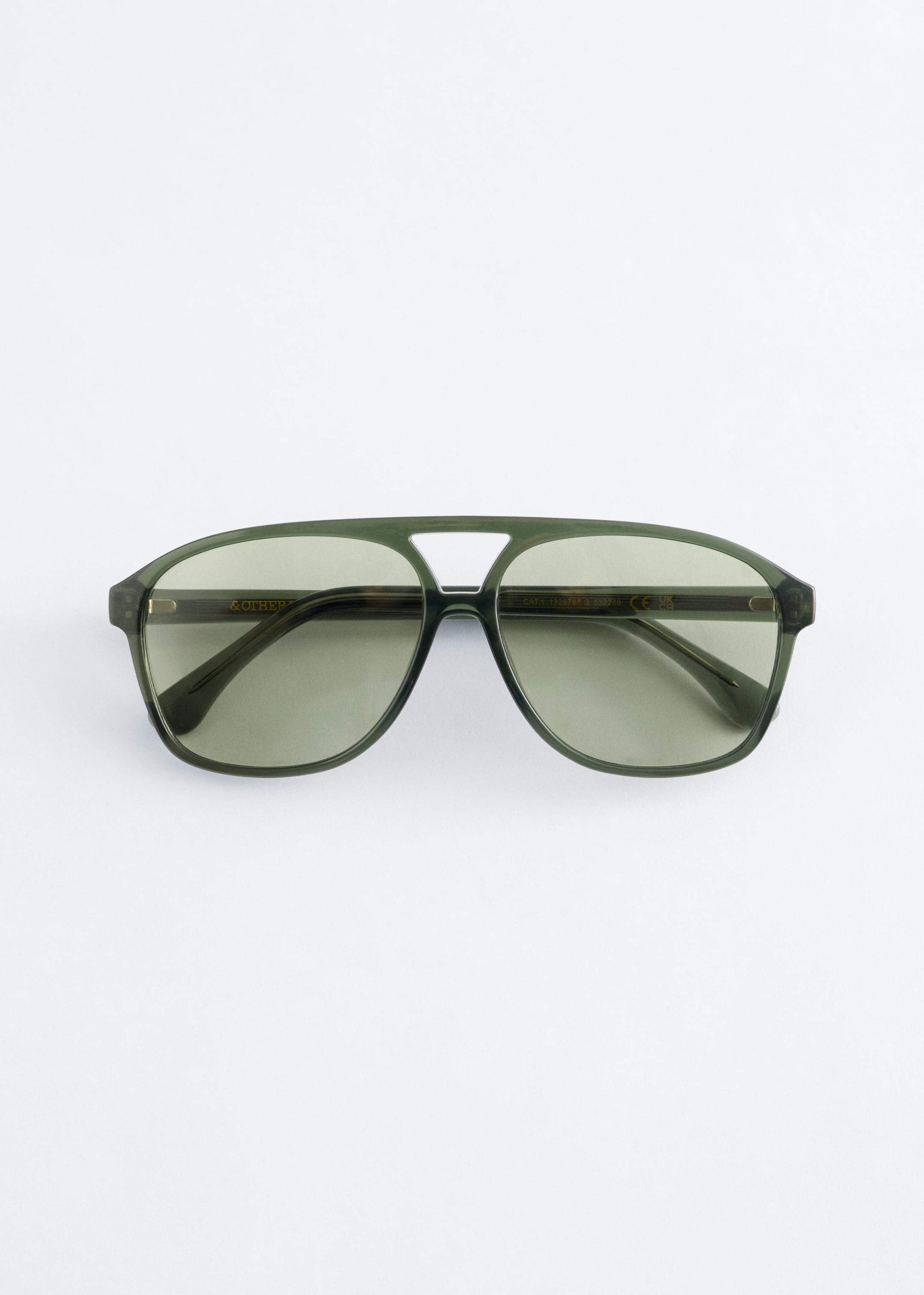Agrandir l'image: Lunettes de soleil surdimensionnées de style aviateur positionnées à l'AVANT, avec une monture translucide vert foncé aux bords arrondis, une barre sourcilière classique et des verres teintés verts. Des branches fines s'étendent sur les côtés.