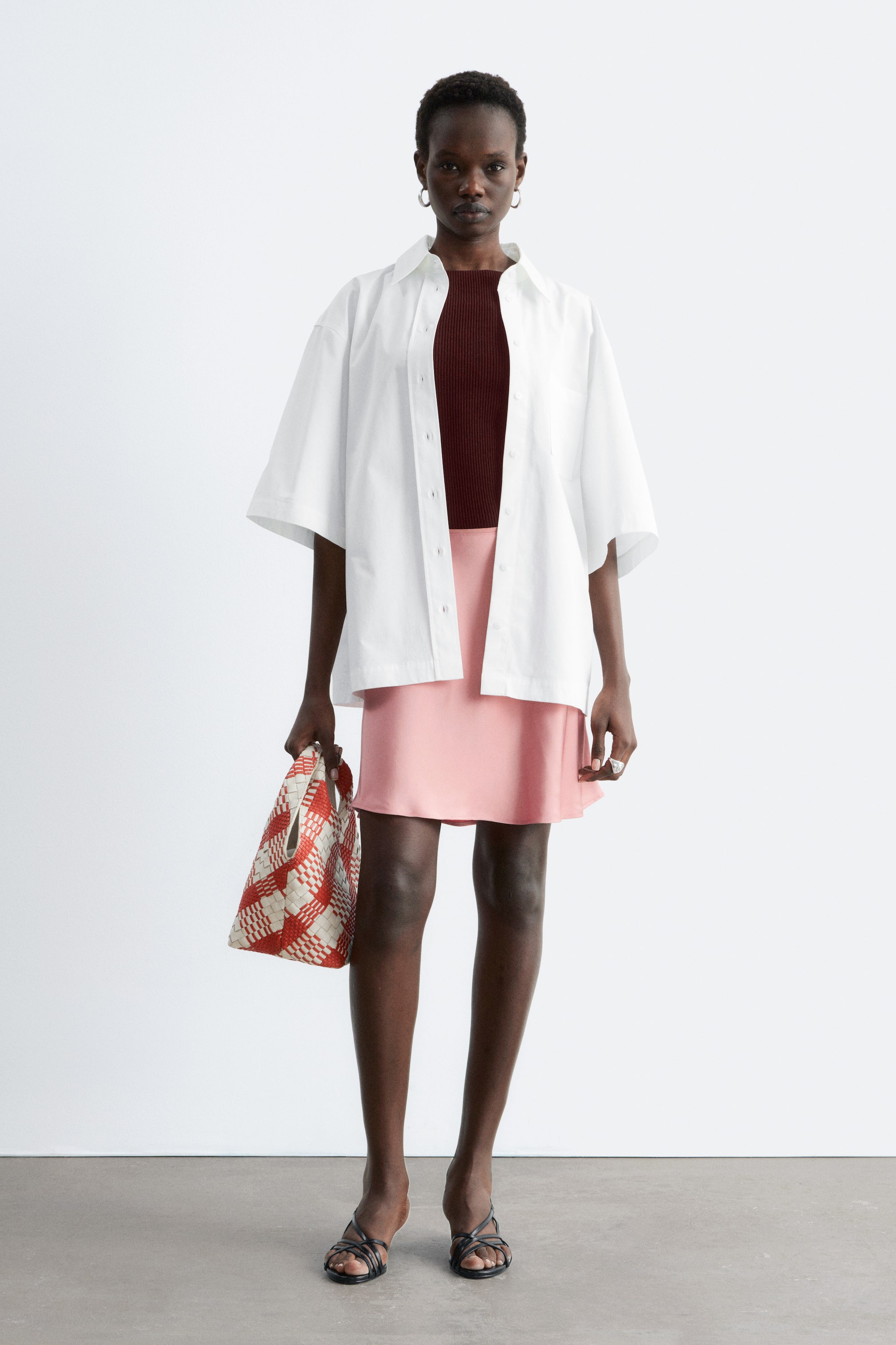 Nagyobb kép megtekintése: A rózsaszín mini szoknya sima, A-vonalú sziluettet mutat elölről nézve, finom fényességgel, térd fölé érve.