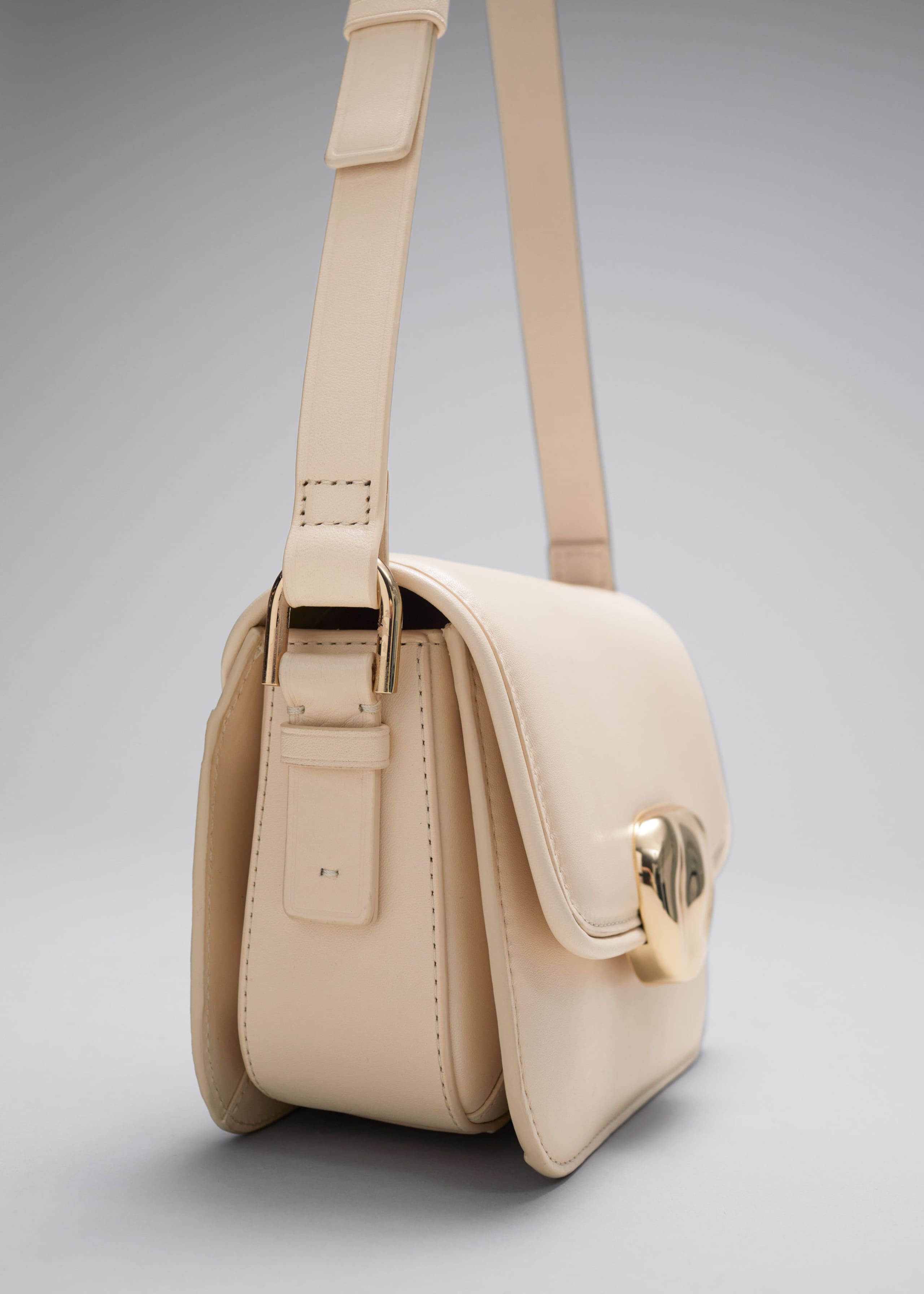 Kleine Ledertasche mit skulpturaler Schnalle - Creme - Stillleben