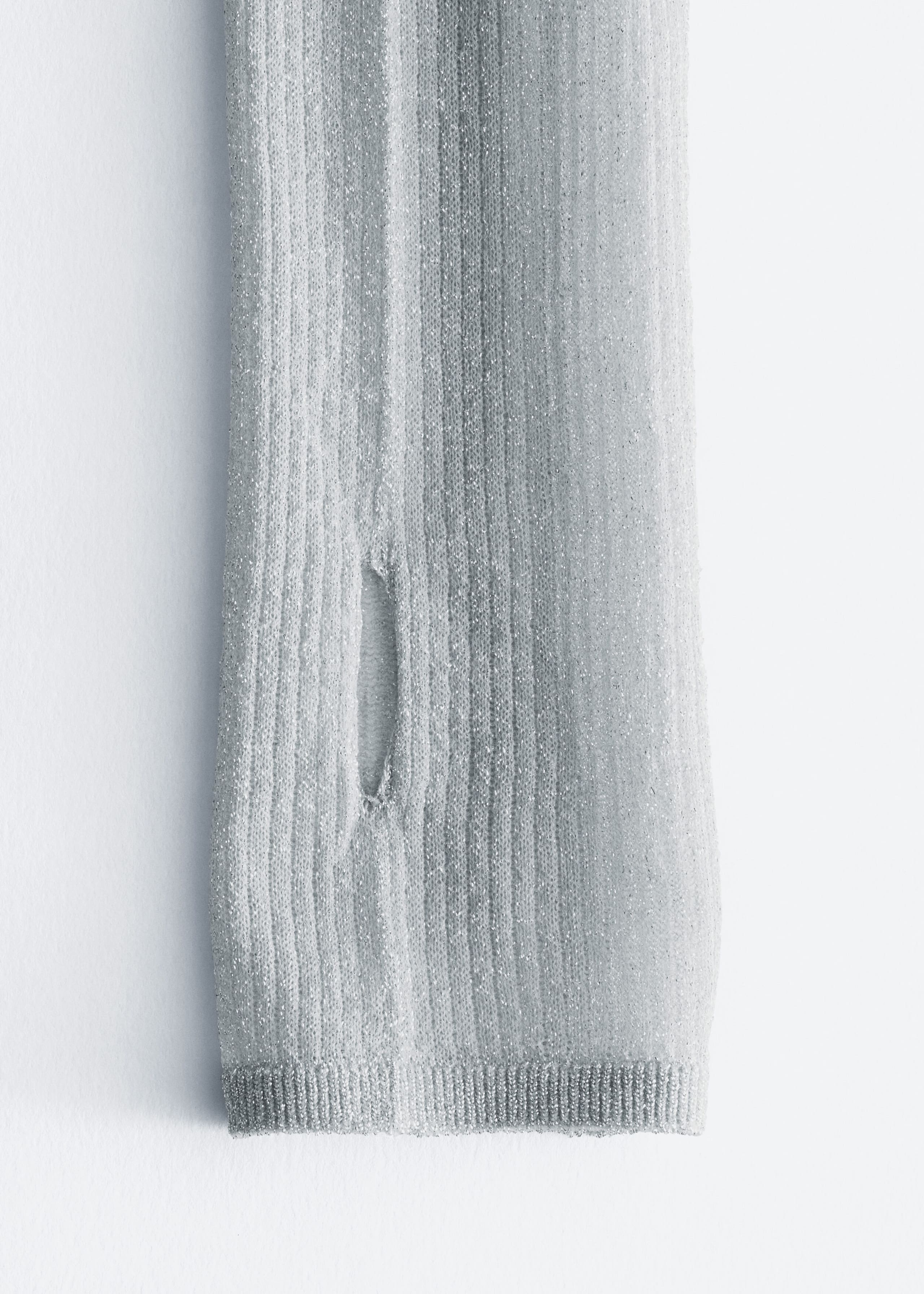 A silver metallic rib-knit sleeve features a vertical thumbhole opening near the cuff. The sleeve ends in a finely ribbed hem.