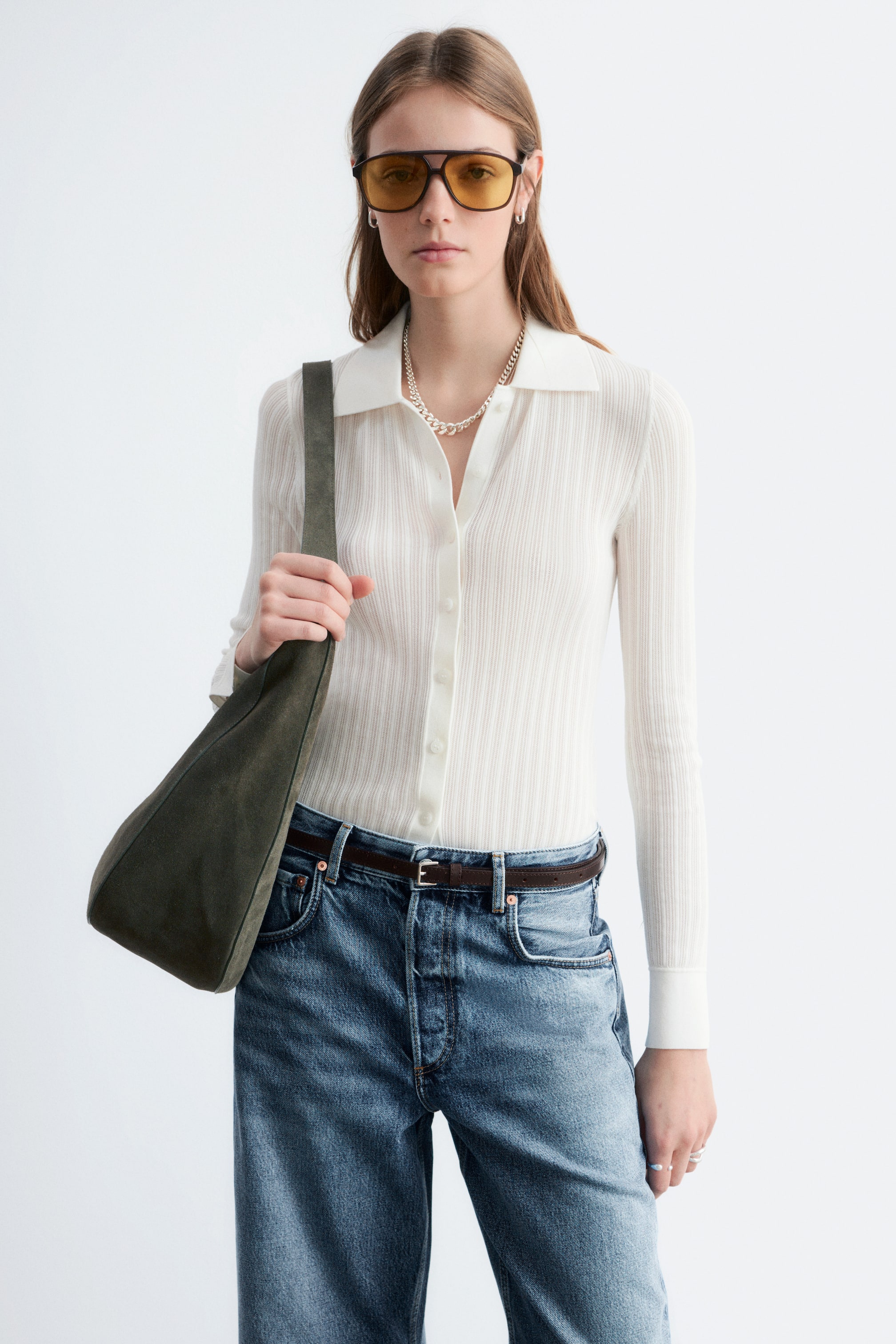 Agrandir l'image: Un polo blanc à manches longues et côtelé, doté d'un col classique et d'une patte de boutonnage sur le devant, mettant en valeur une silhouette ajustée.