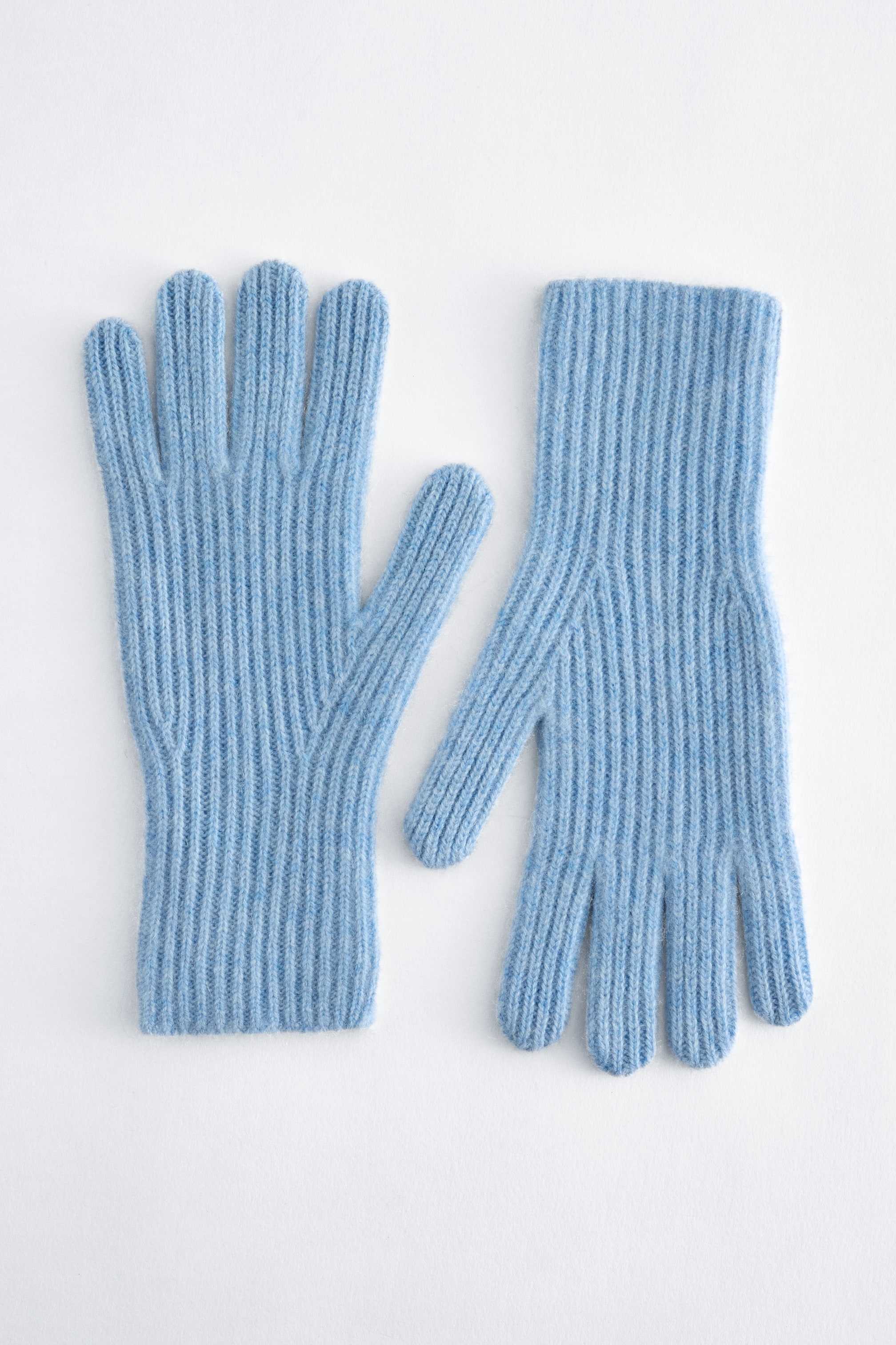 Größeres Bild anzeigen: Ein Paar hellblaue Kaschmirhandschuhe liegt flach und zeigt ihr strukturiertes Rippstrick-Design. Ein Handschuh ist nach oben ausgerichtet, der andere nach unten, sodass Vorder- und Rückseite sichtbar sind.
