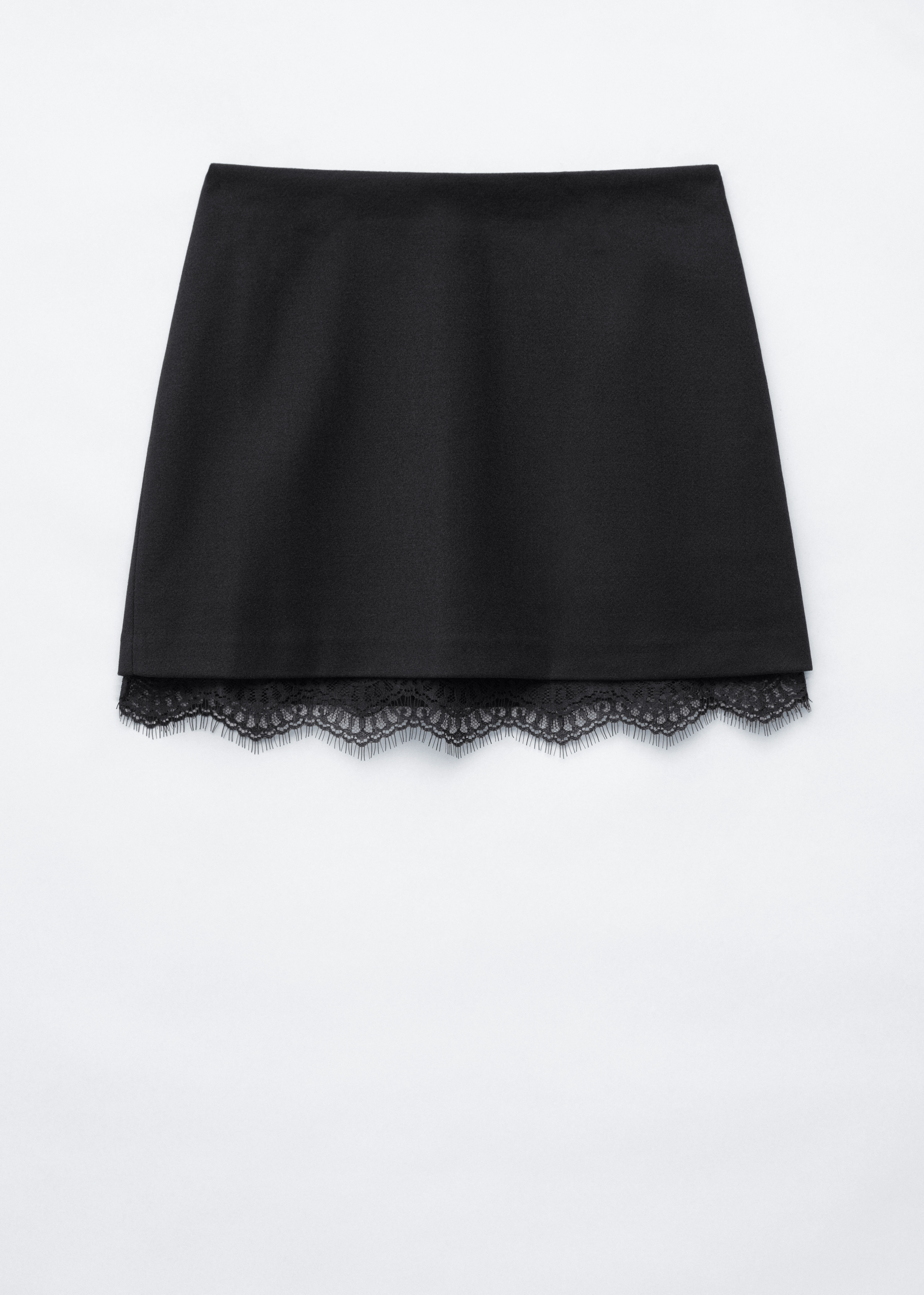 Une mini-jupe noire taille haute avec une sous-couche en dentelle apparente au niveau de lâourlet est portÃ©e par le mannequin. La jupe est associÃ©e Ã  un pull en maille rayÃ© noir et blanc et Ã  des mocassins noirs.