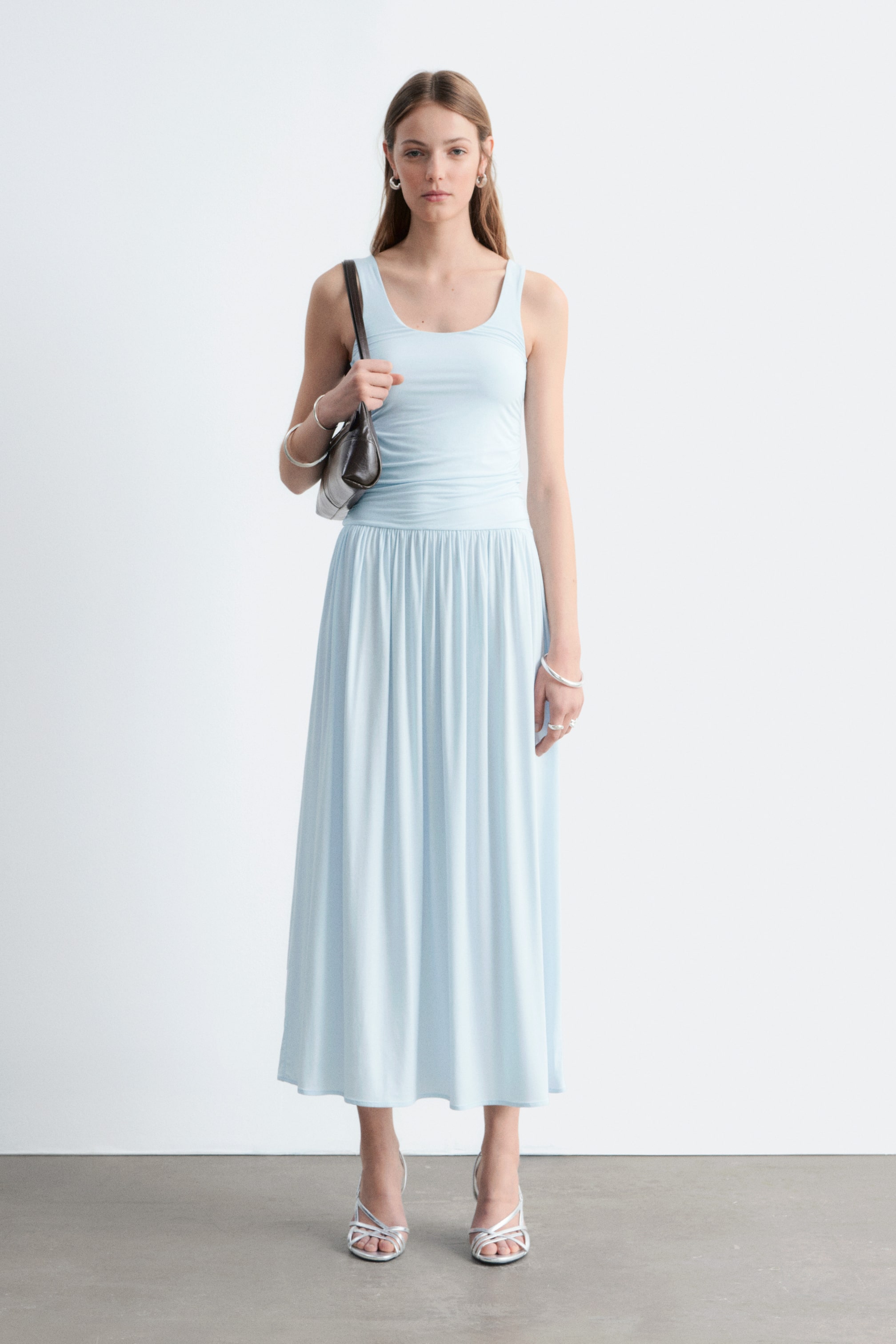 Προβολή μεγαλύτερης εικόνας: Ένα ανοιχτό μπλε μάξι φόρεμα παρουσιάζεται, με ένα μπούστο τύπου δεξαμενής με στρογγυλή λαιμόκοψη και διακριτικό σούρωμα στη μέση, που καταλήγει σε μια μαζεμένη μέση και μια μακριά, πλήρη φούστα.
