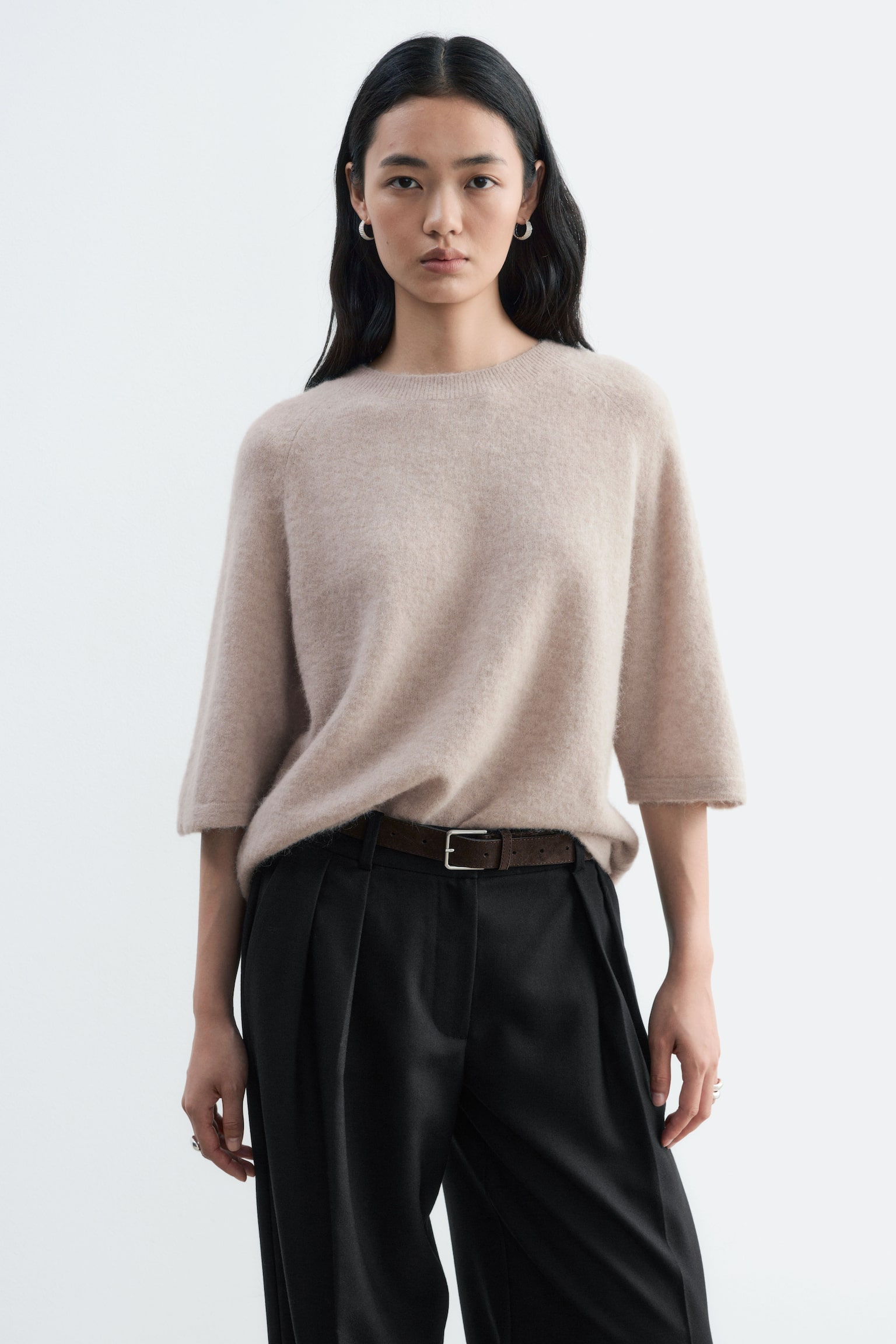 Forsiden af en lys beige strikket crewneck t-shirt viser sin bløde, børstede tekstur. Den er designet med raglanærmer, der slutter ved albuen, og en ribbet crewneck-krave. - 1