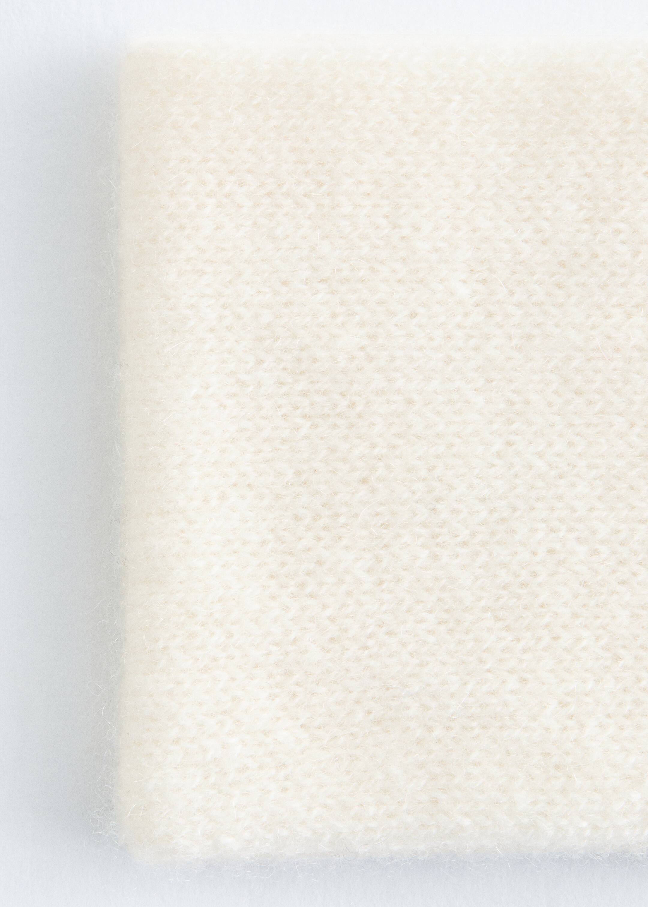 Agrandir l'image: Le bandeau en cachemire de couleur crème est présenté en gros plan, révélant sa texture finement tricotée avec une apparence douce et duveteuse. Un bord plié est visible le long du côté gauche.