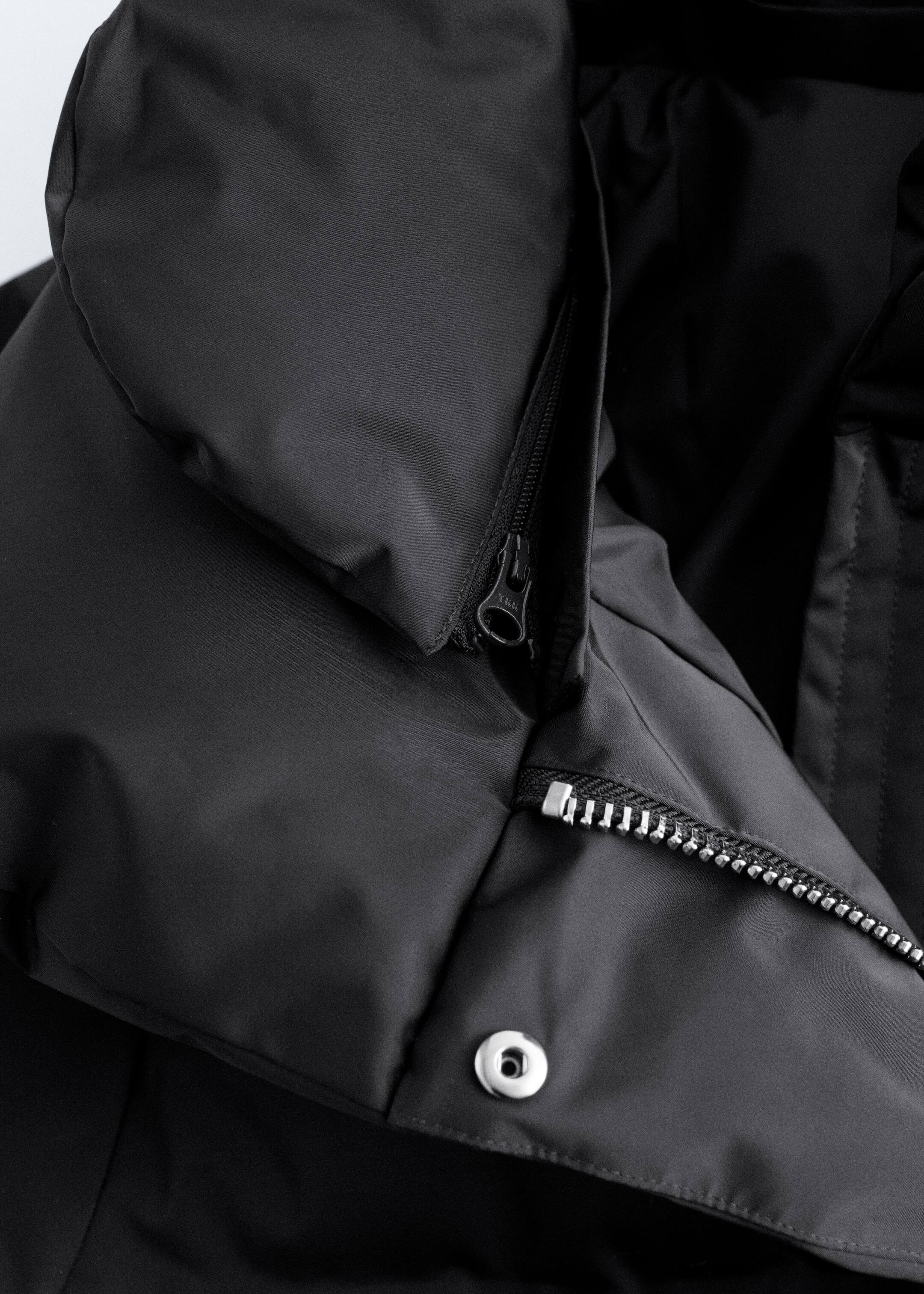 View larger image: A black puffer jacket is angled to its upper left side, featuring heavy padding and a double stand collar. The inner collar is showing a black zipper, and a silver-toothed zipper with a silver press button are visible on the front placket.