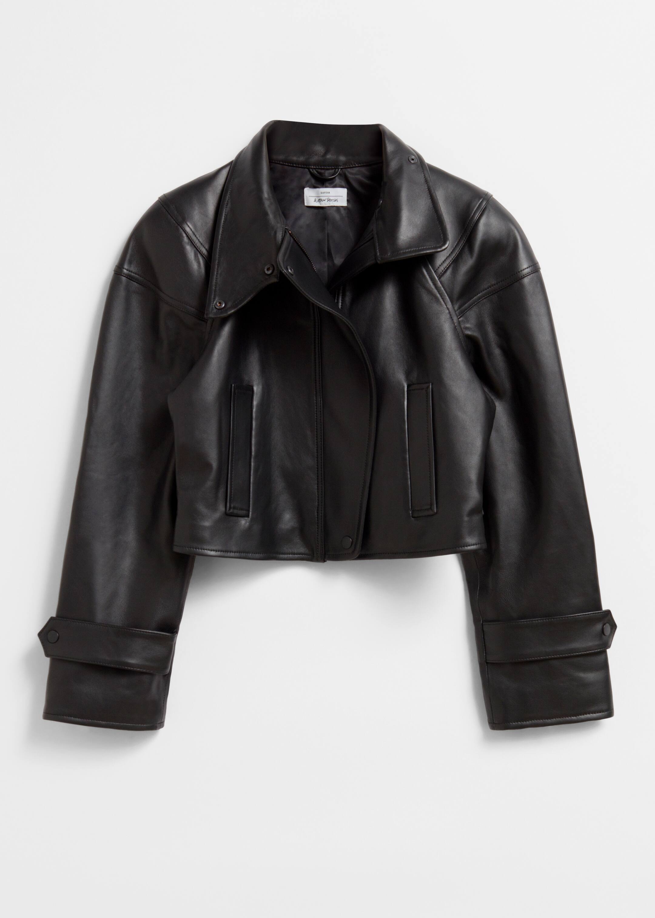 Größeres Bild ansehen: Eine schwarze, abgeschnittene Lederjacke wird von vorne gezeigt, mit einem glatten Finish, einem breiten, spitzen Kragen und abgerundeten, gepolsterten Schultern. Sie ist mit einer Frontleiste ausgestattet, die mit drei Druckknöpfen gesichert ist, zwei vertikalen Leistentaschen und breiten Manschetten mit Druckknopf-Laschen.