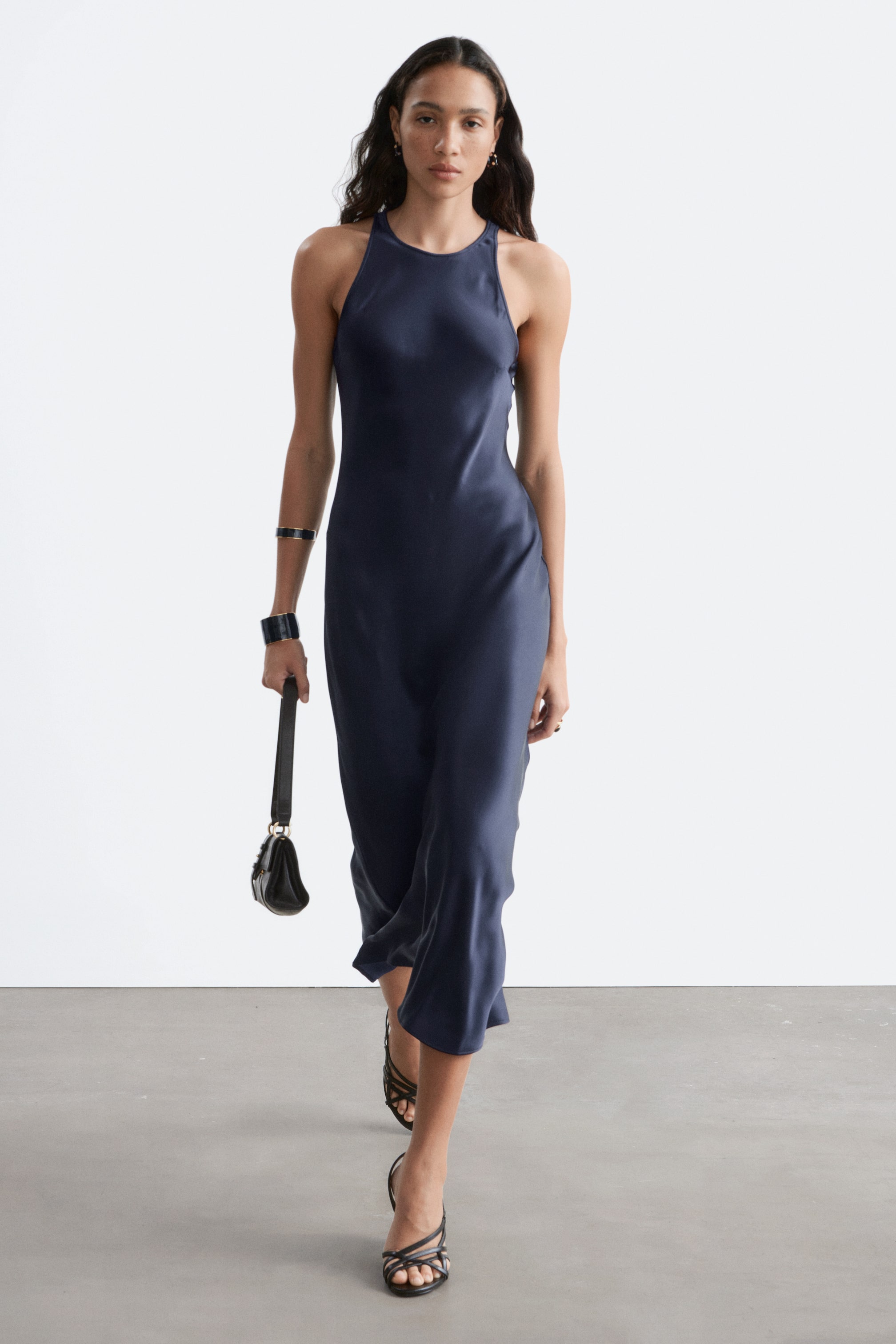 Agrandir l'image: Une robe midi en satin bleu foncé avec un décolleté licou et une silhouette fluide, tombant sous les genoux.