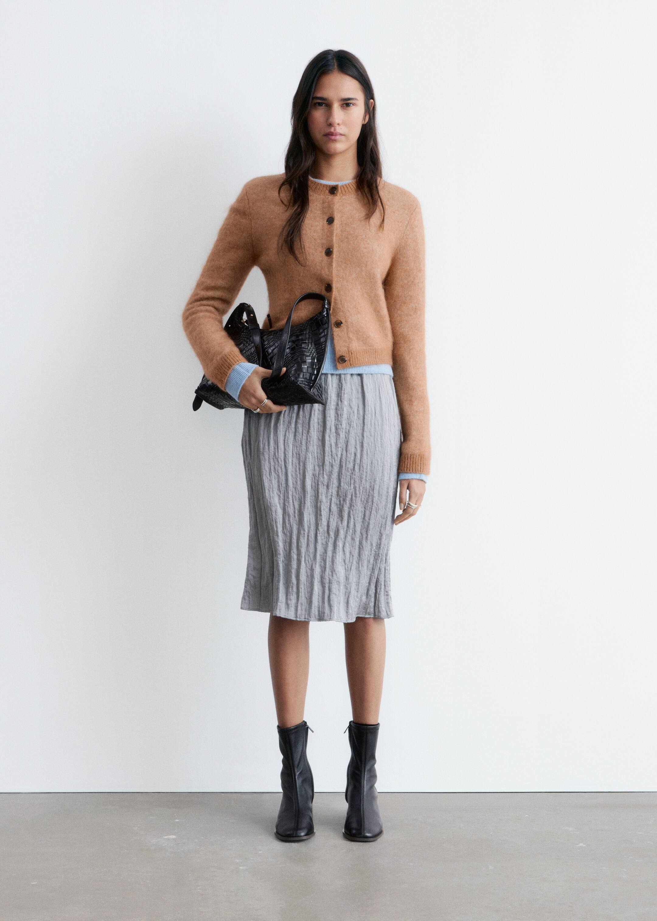 Größeres Bild ansehen: Eine schwarze, geflochtene Lederhandtasche wird präsentiert und zeigt ihre fein gearbeitete Korbgeflechtstruktur, zwei obenliegende Tragegriffe und ihre strukturierte, rechteckige Form.