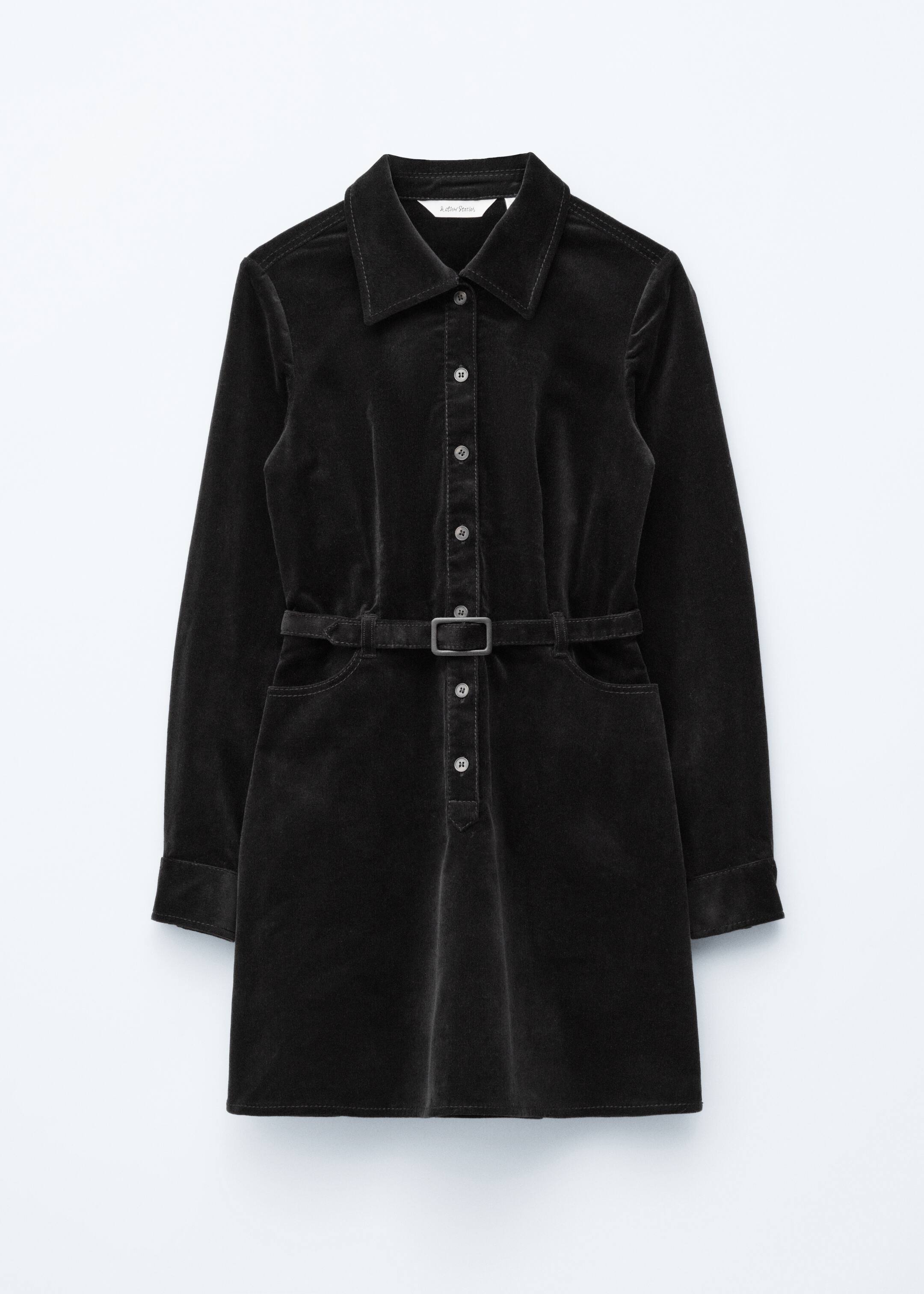 Agrandir l'image: Une robe mini en velours noir expose son devant, avec un col classique et une patte de boutonnage complète avec des boutons argentés. Elle est conçue avec des manches longues, des poignets boutonnés, une ceinture intégrée avec une boucle rectangulaire cintrant la taille, et deux poches avant.