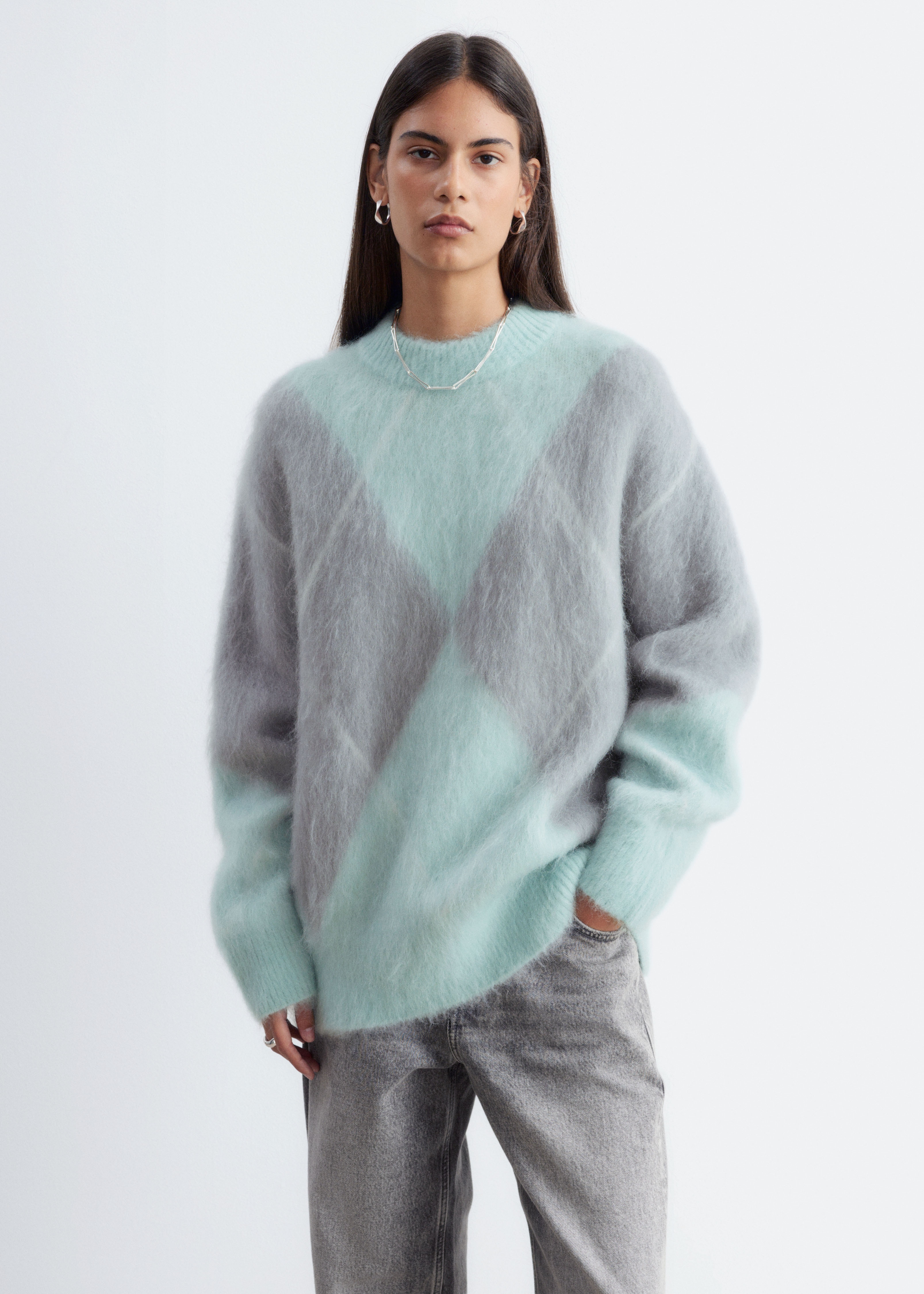 Un pulover din amestec de mohair este prezentat din faÈÄ, evidenÈiind o siluetÄ oversized, cu un model jacquard argyle Ã®n verde mentÄ Èi gri. Puloverul afiÈeazÄ un tricot moale, cu texturÄ pufoasÄ, cu guler rotund ribat, manÈete ribate Èi tiv ribat.
