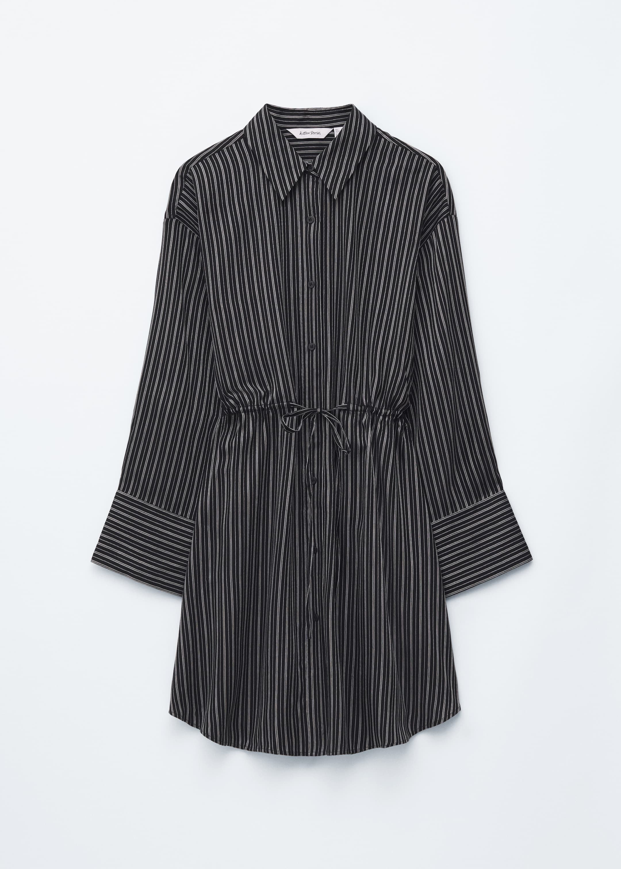 Agrandir l'image: Une robe-chemise à rayures noires et blanches est présentée de face, avec un col pointu et une patte de boutonnage sur toute la longueur. Elle est conçue avec des manches longues se terminant par des poignets larges et pliés, et un cordon de serrage visible resserre la taille, noué en un nœud.