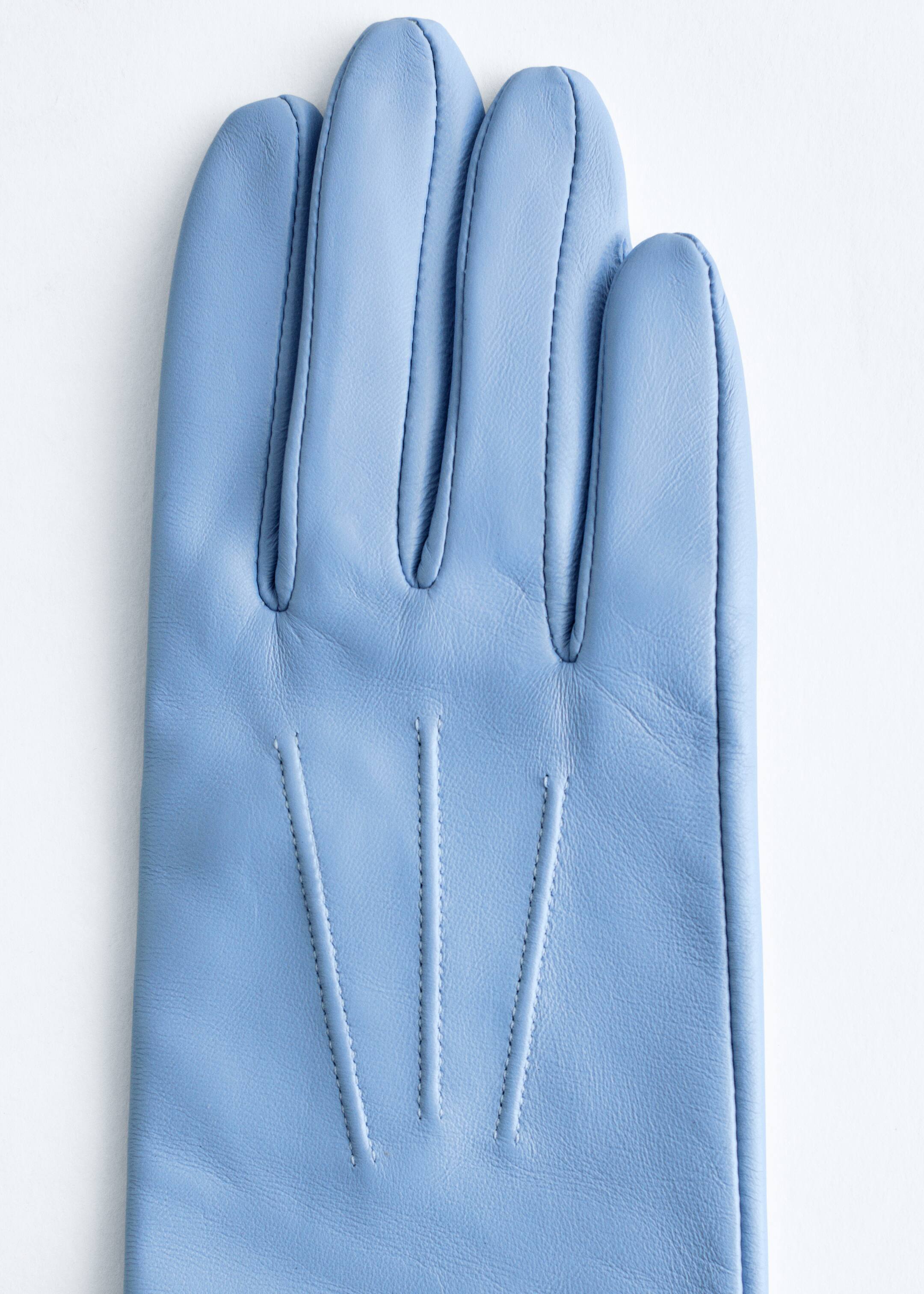 Größeres Bild ansehen: Ein hellblauer Lederhandschuh wird von vorne präsentiert und zeigt den Handrücken mit drei vertikalen genähten Falten und sichtbaren Nähten entlang der Fingernaht.