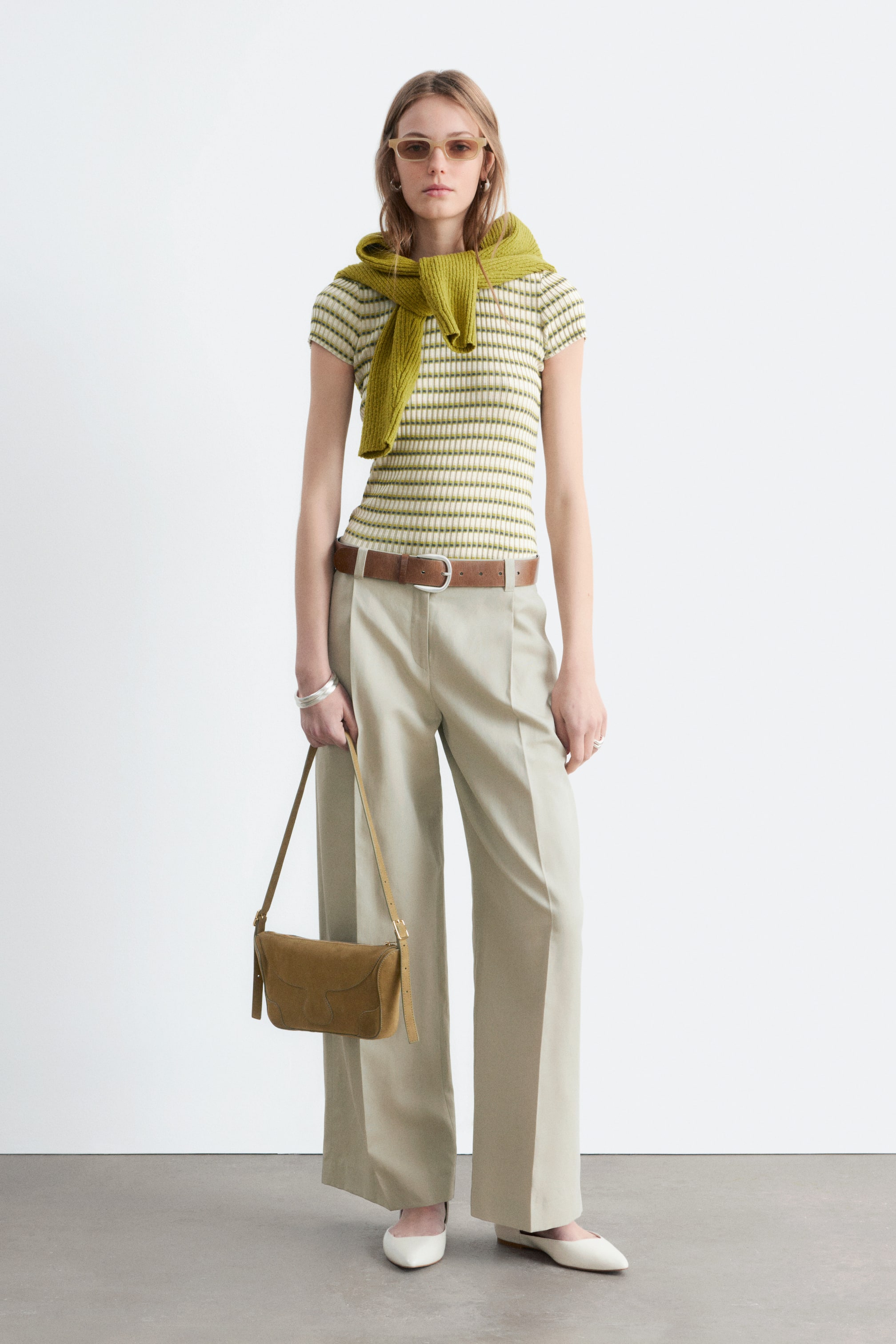 Agrandir l'image: Le haut à manches courtes en maille côtelée présente des rayures horizontales vert citron sur un fond crème, avec un pull côtelé vert drapé sur les épaules.