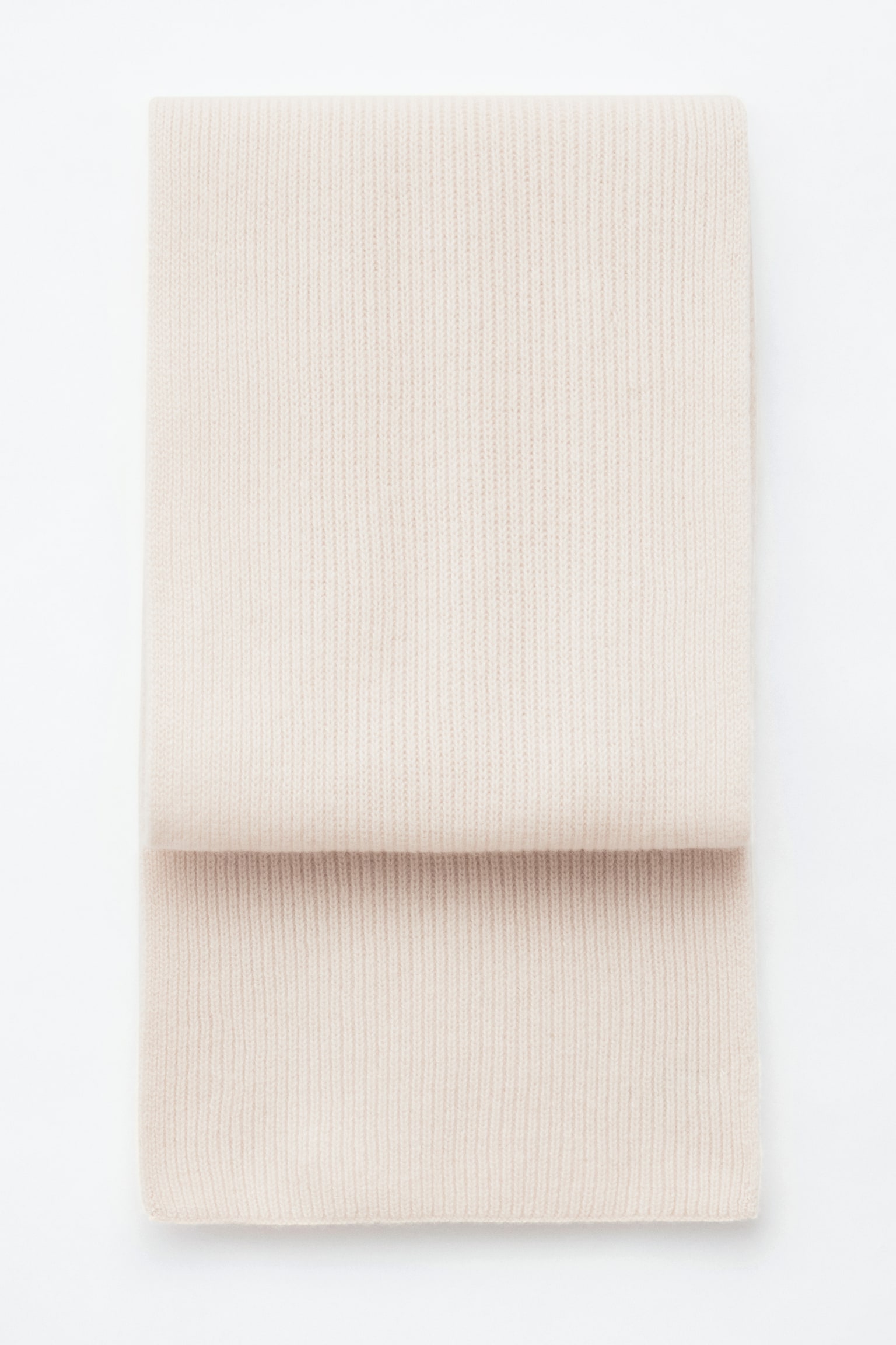 En ljuskrämfärgad stickad halsduk i kashmir med vertikal ribbad finish ligger vikt platt och visar upp sin mjuka textur och rena, raka kanter. - 1