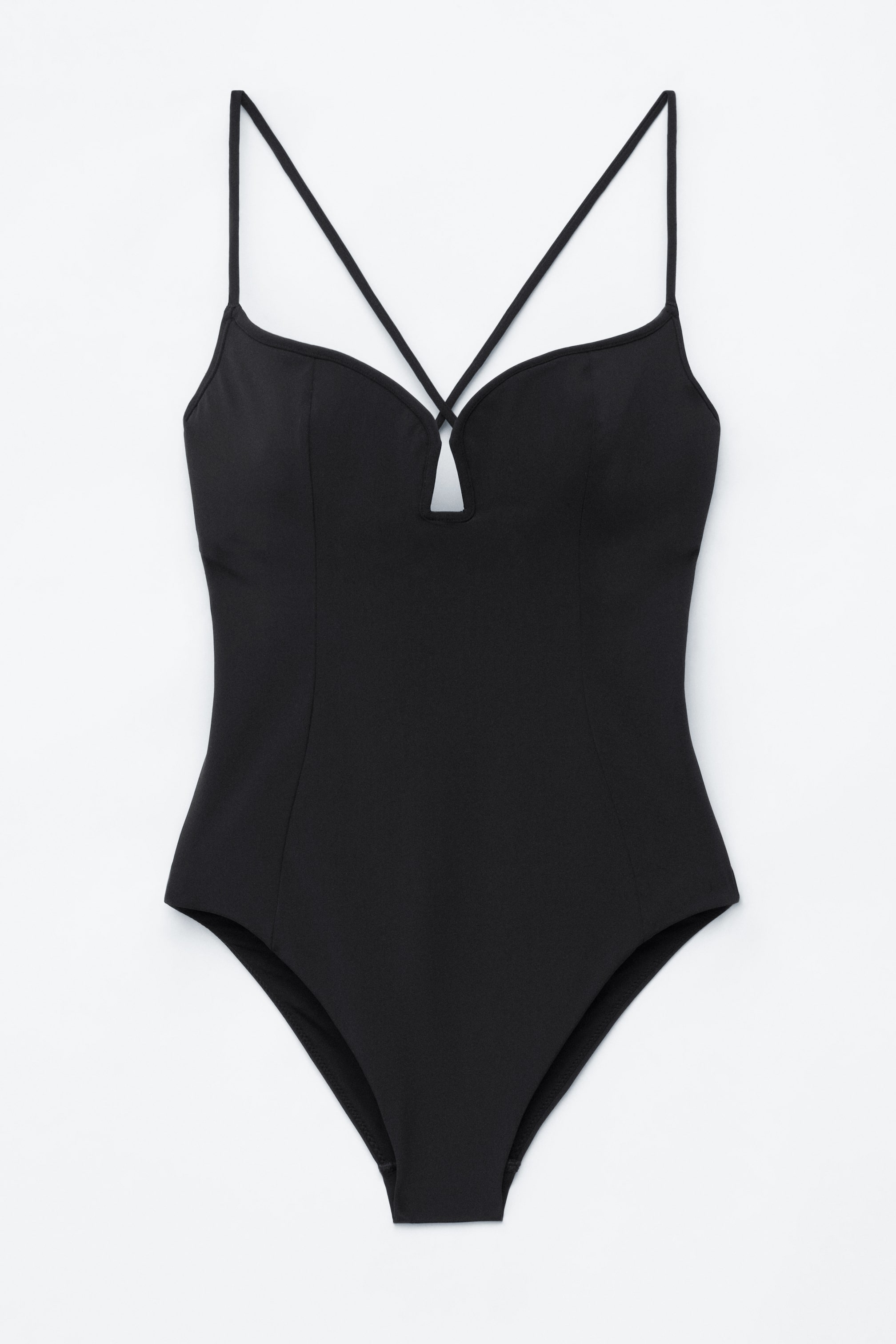 Agrandir l'image: Un maillot de bain une pièce noir est présenté de face, avec un décolleté en triangle doté d'une petite découpe en forme de V et de fines bretelles croisées sur la poitrine. Des coutures visibles sculptent le corsage et en définissent la structure.