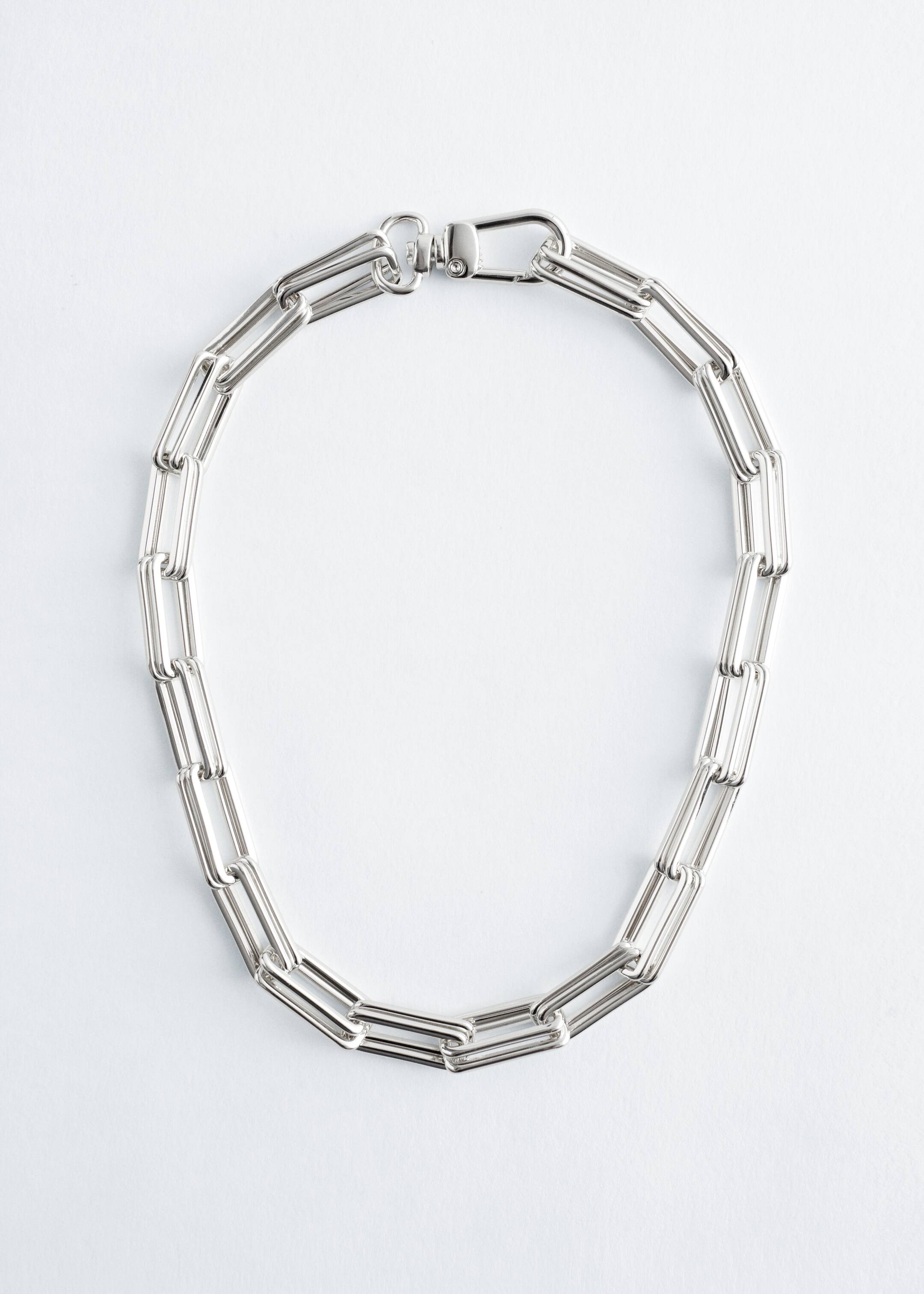 Agrandir l'image: Un collier à maillons épais de couleur argent est posé à plat, formant une forme en U. Il est constitué de maillons rectangulaires allongés et est fermé par un fermoir à mousqueton pivotant, indiquant un ajustement court.
