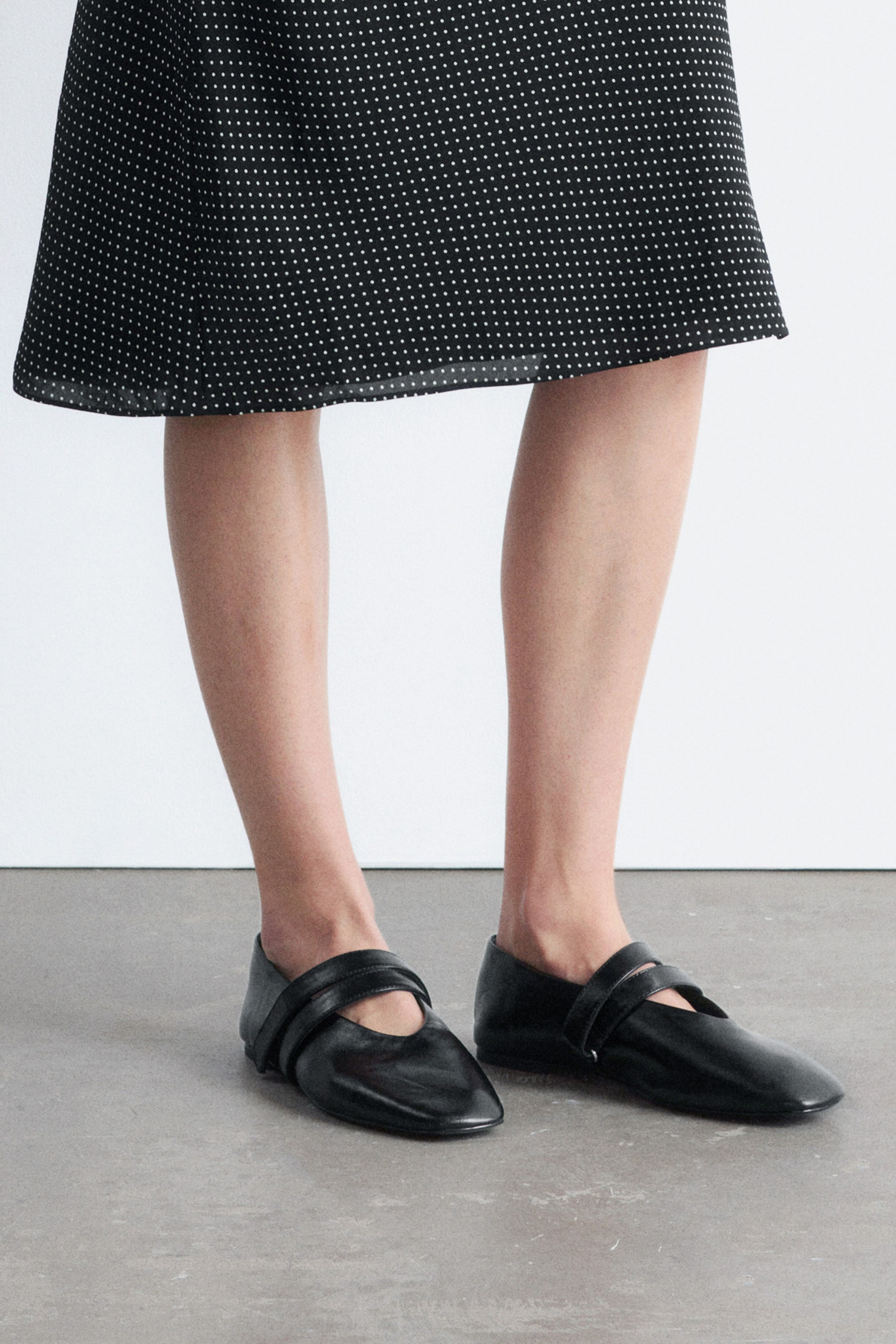 Se større billede: Sort glat læder ballerina flats har en minimalistisk silhuet med en blød firkantet tå. Krydsende stropper sikrer flats med velcro.
