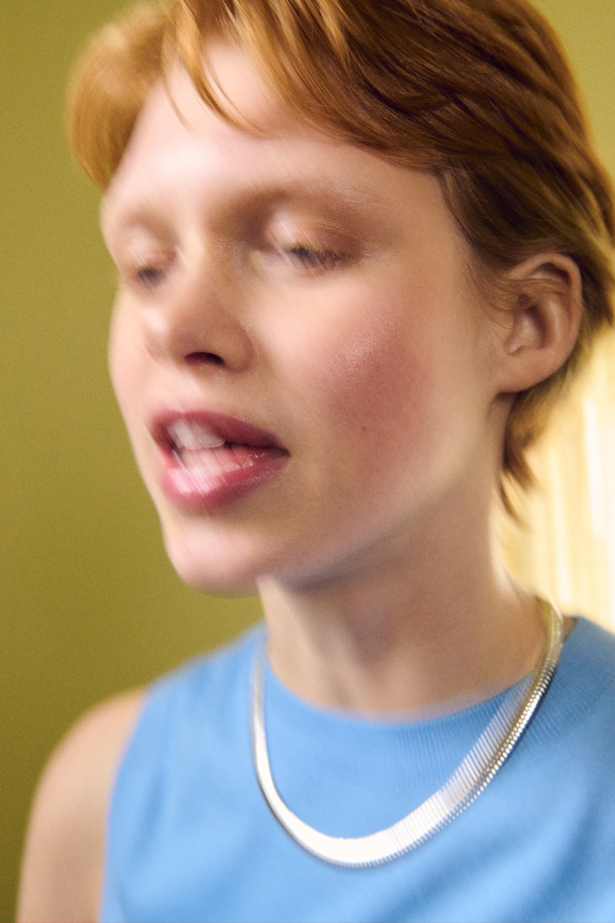 View larger image: A silver-toned herringbone chain necklace curves elegantly around the neck, resting on a light blue round-neck sleeveless top.