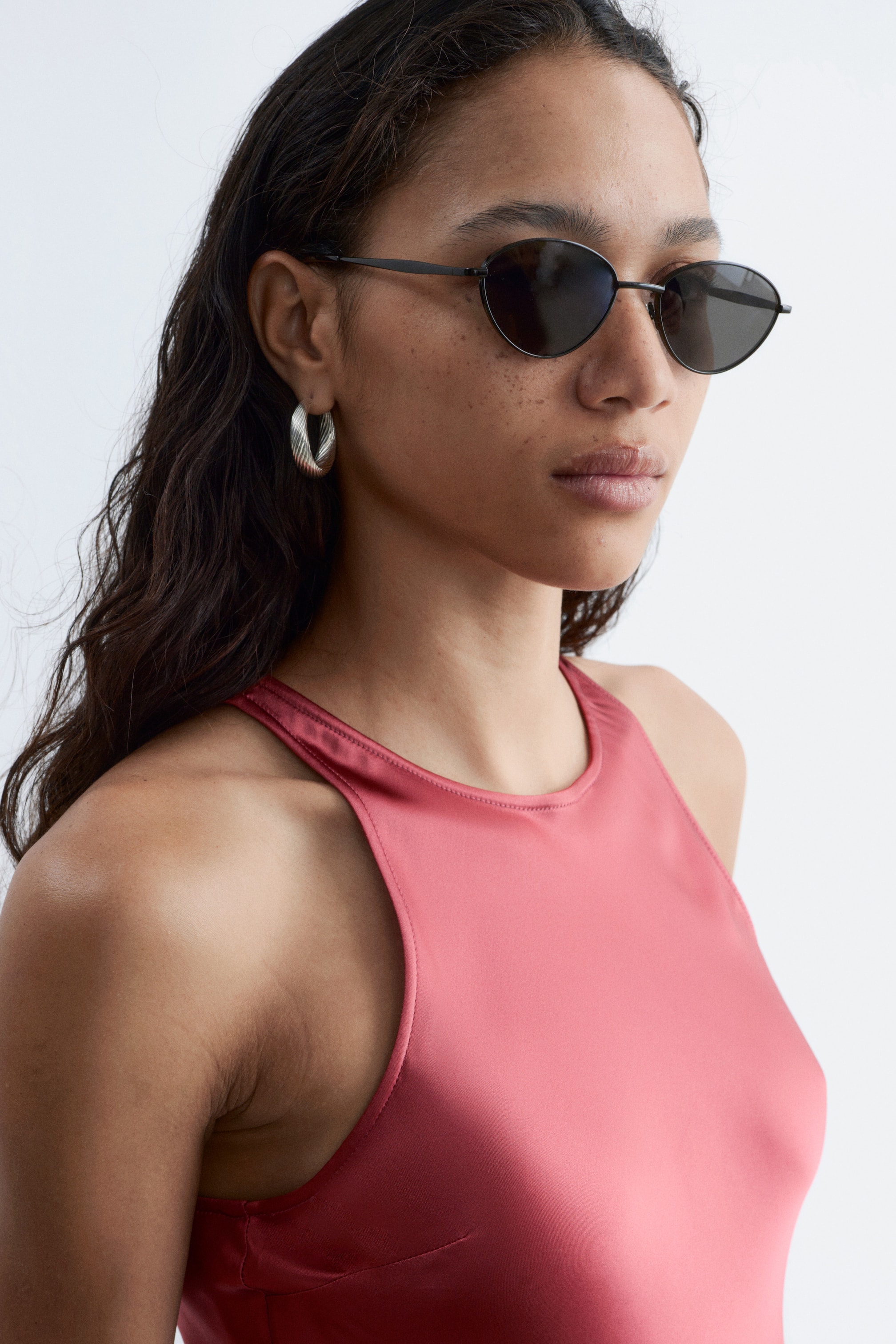 Visa större bild: En rosafärgad topp presenterar ett slätt, satinliknande tyg, en hög, rundad halsringning och högt skurna ärmhål som böjer sig inåt mot halsen.