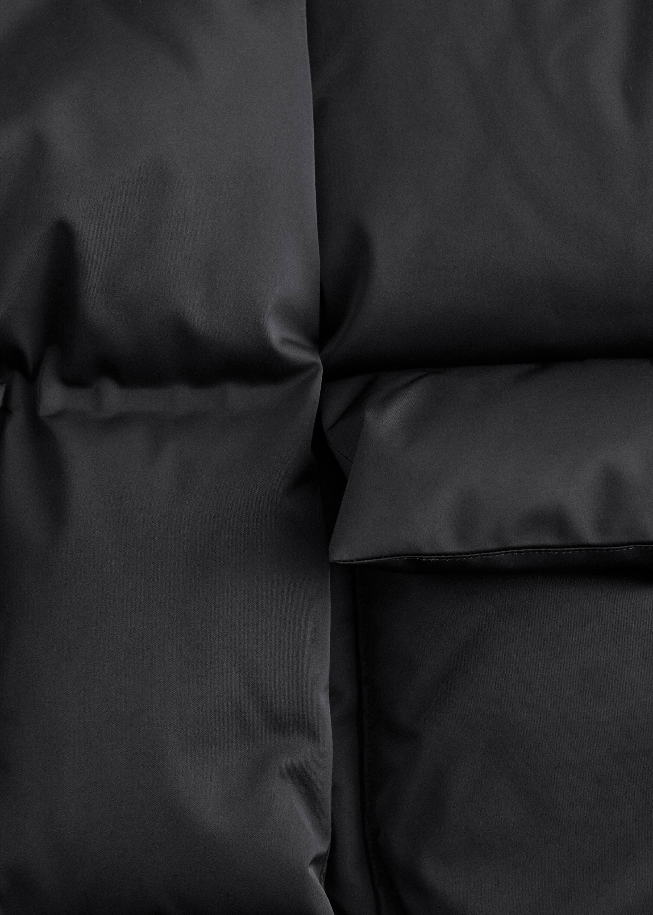 View larger image: A black puffer jacket is displaying its heavily padded, heat-pressed panels. A large, padded patch pocket with a flap is visible on the right side.