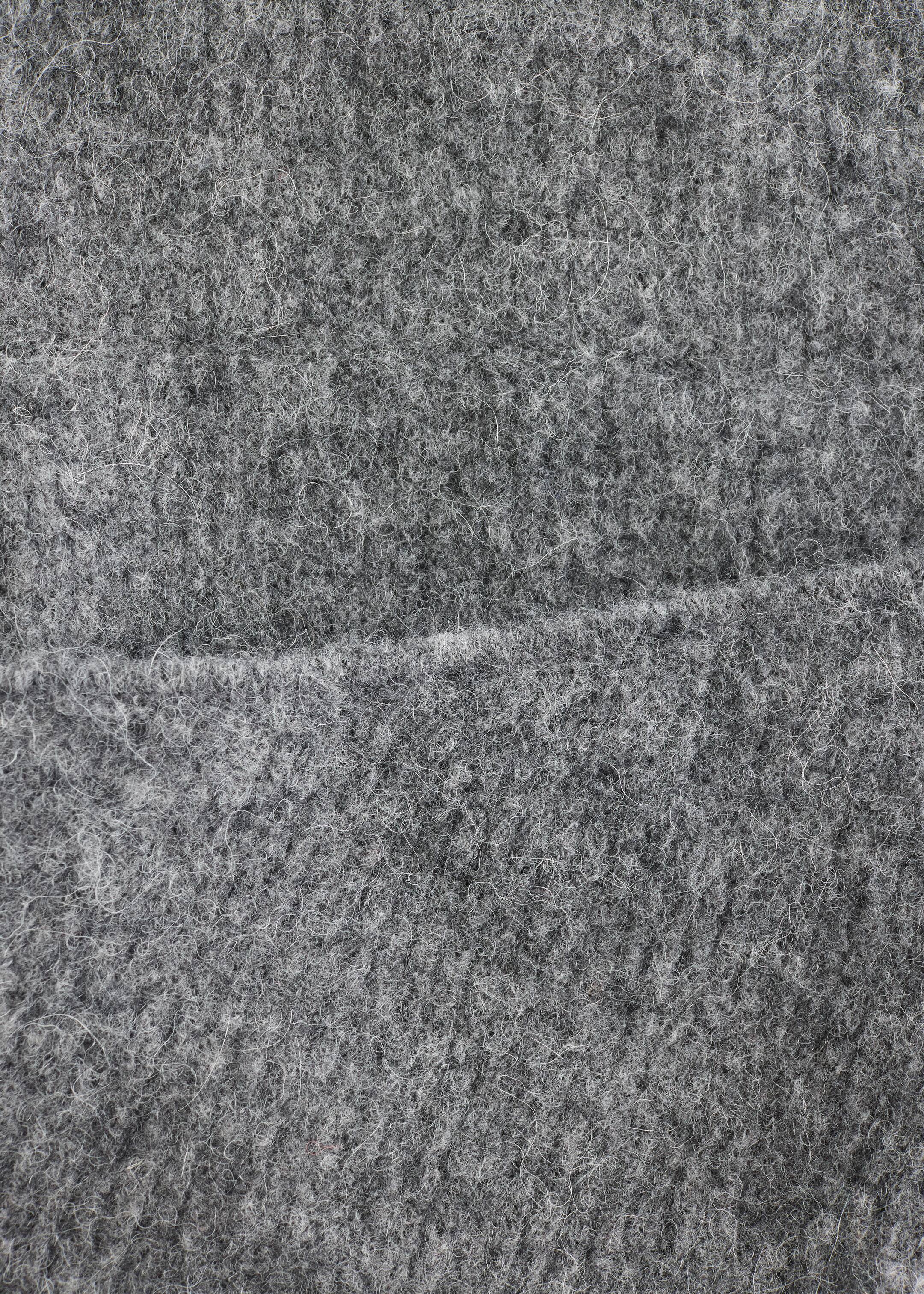 Größeres Bild anzeigen: Ein grauer Stoff zeigt eine dichte, flauschige Textur mit sichtbaren hellgrauen Fasern, und eine horizontale Naht verläuft durch seine Mitte.