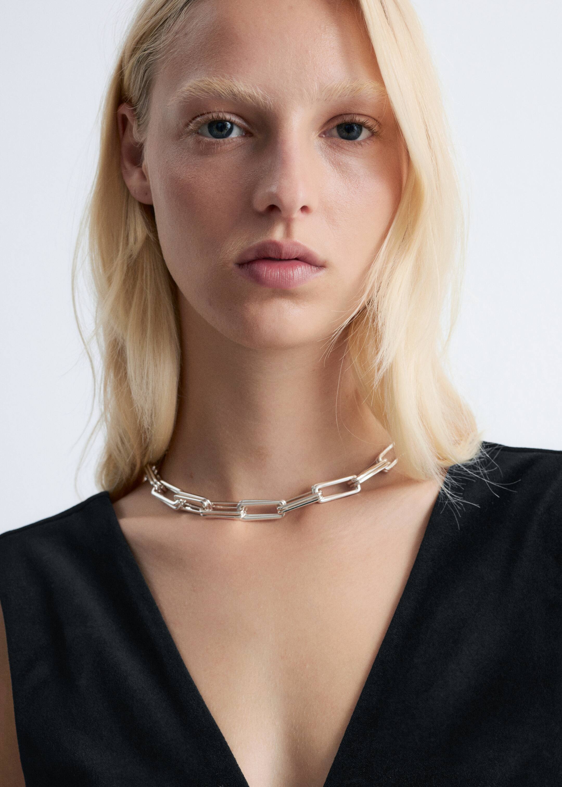 Visualizza immagine più grande: Una collana a catena massiccia dal tono argentato è appoggiata in alto sulla clavicola. Presenta grandi maglie rettangolari allungate.