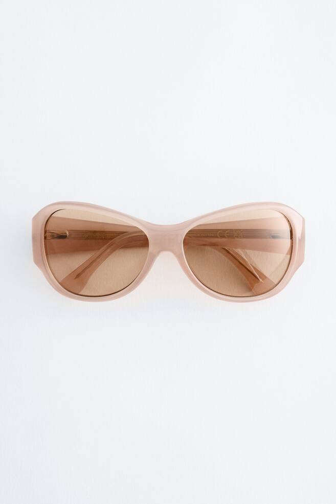 Les lunettes de soleil présentent des montures courbées, surdimensionnées, en acétate translucide marron clair avec des verres teintés marron, orientées vers l'avant. - 1
