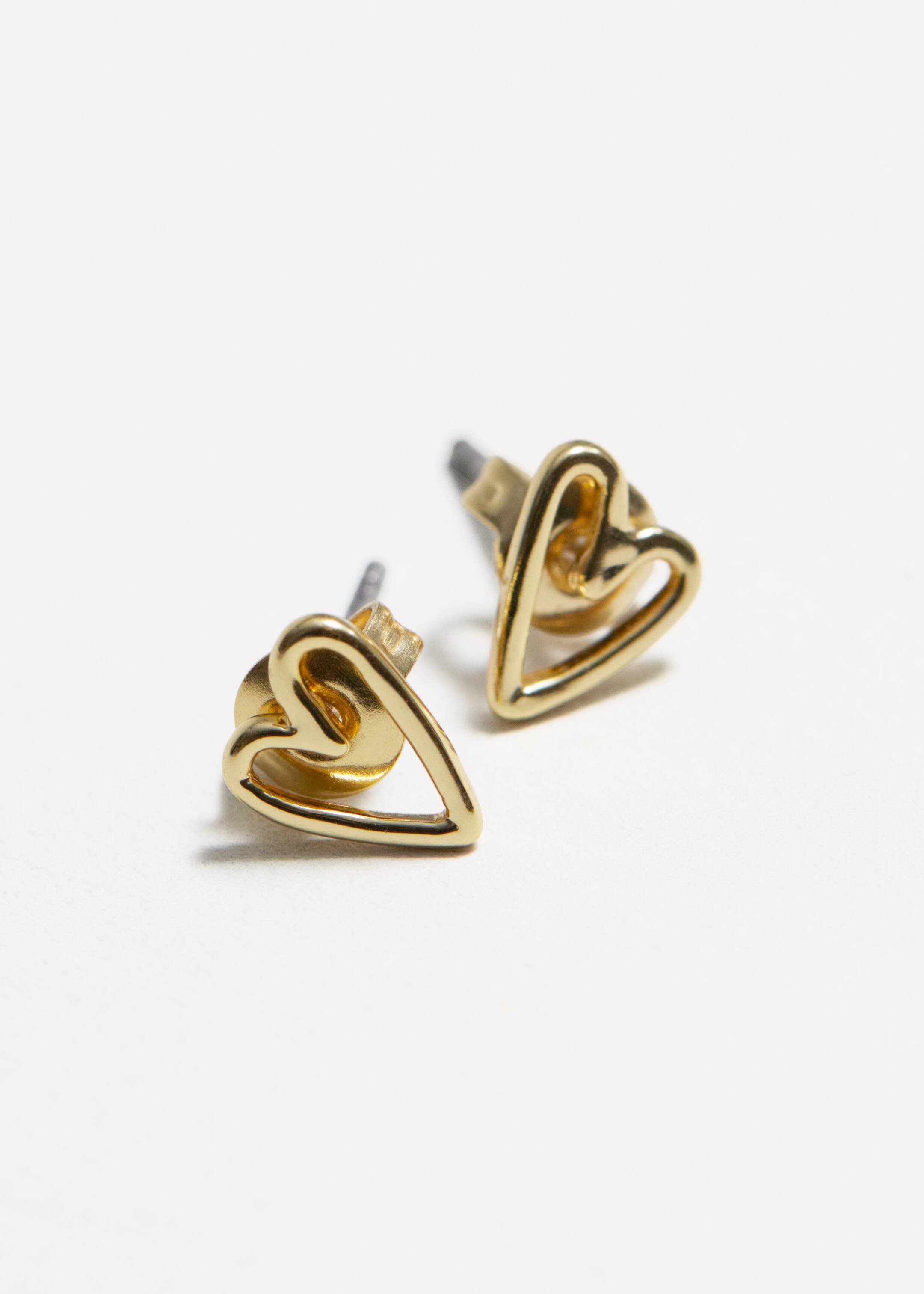 View larger image: A pair of gold-toned stud earrings is presented, each earring featuring an open heart design. The earrings are angled, revealing their three-dimensional structure and the attached back posts.