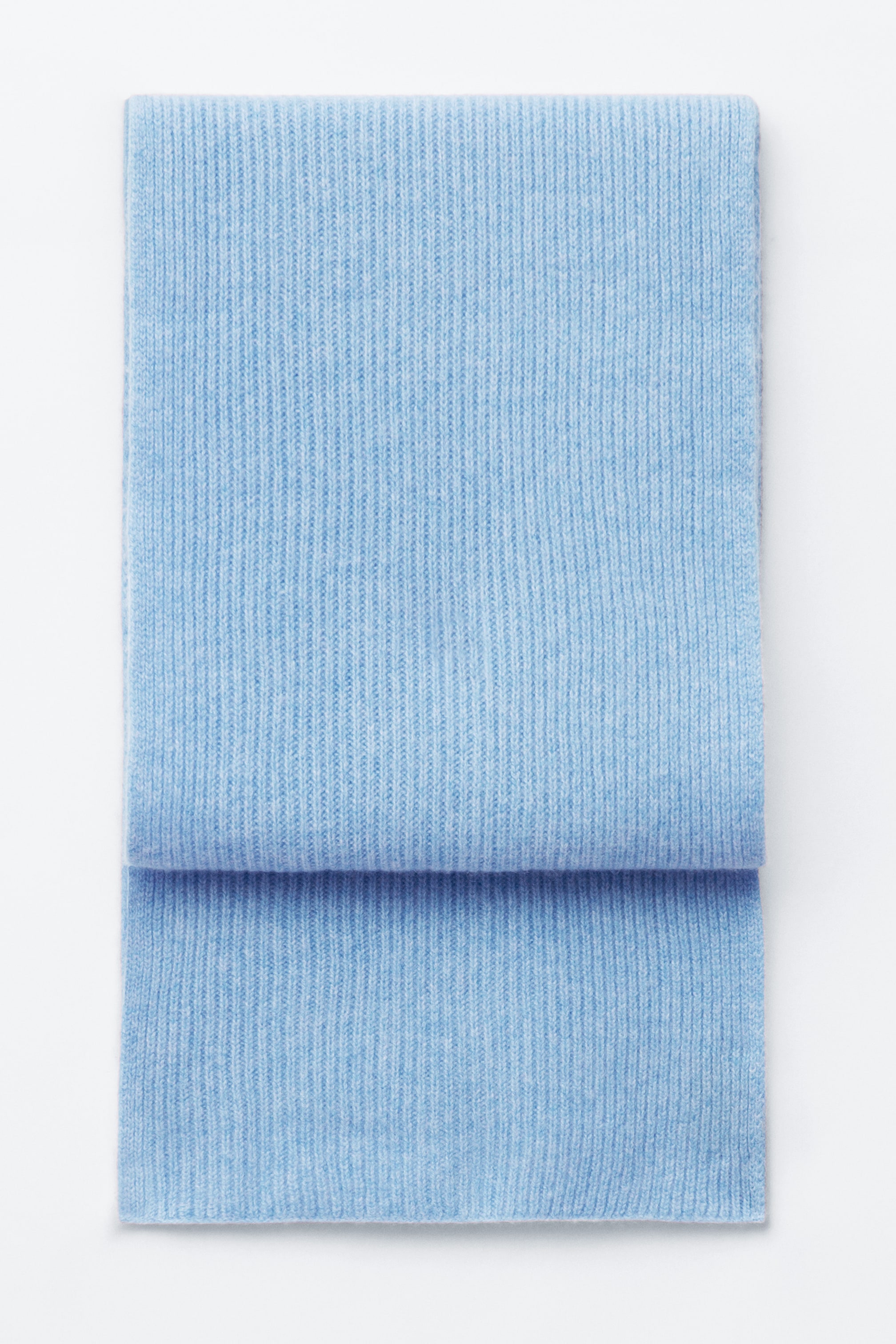 Größeres Bild anzeigen: Ein hellblauer, gerippter Strickschal liegt flach in der Vorderansicht und ist ordentlich gefaltet, um seine weiche, vertikal gerippte Struktur zu präsentieren.