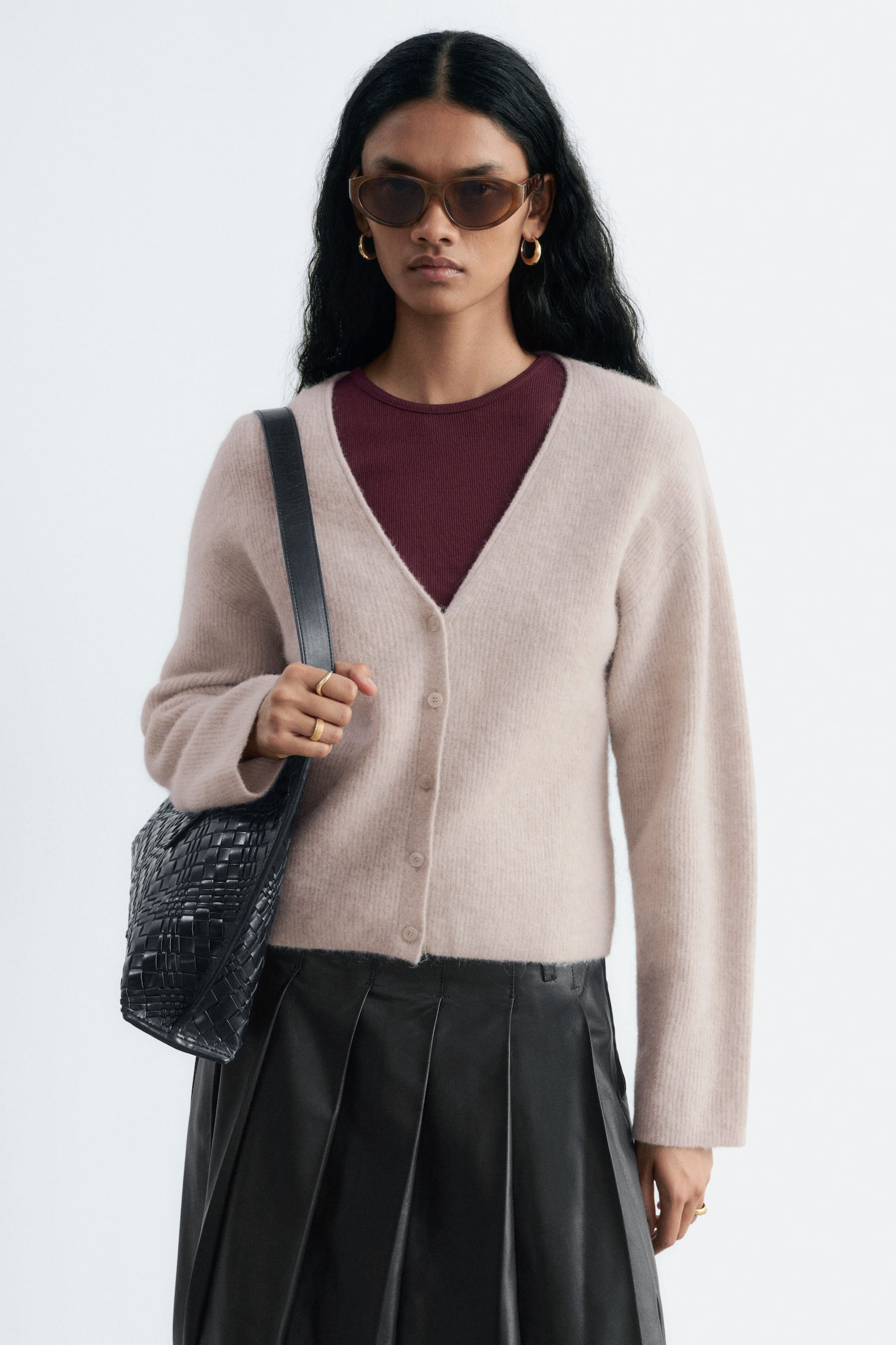 En ljusbeige, fluffig stickad kofta med V-ringning och en framknäppning med sex runda, färgmatchade knappar. Den är designad med långa ärmar, ribbade muddar och en ribbad fåll, vilket ger en kortare silhuett. - 1