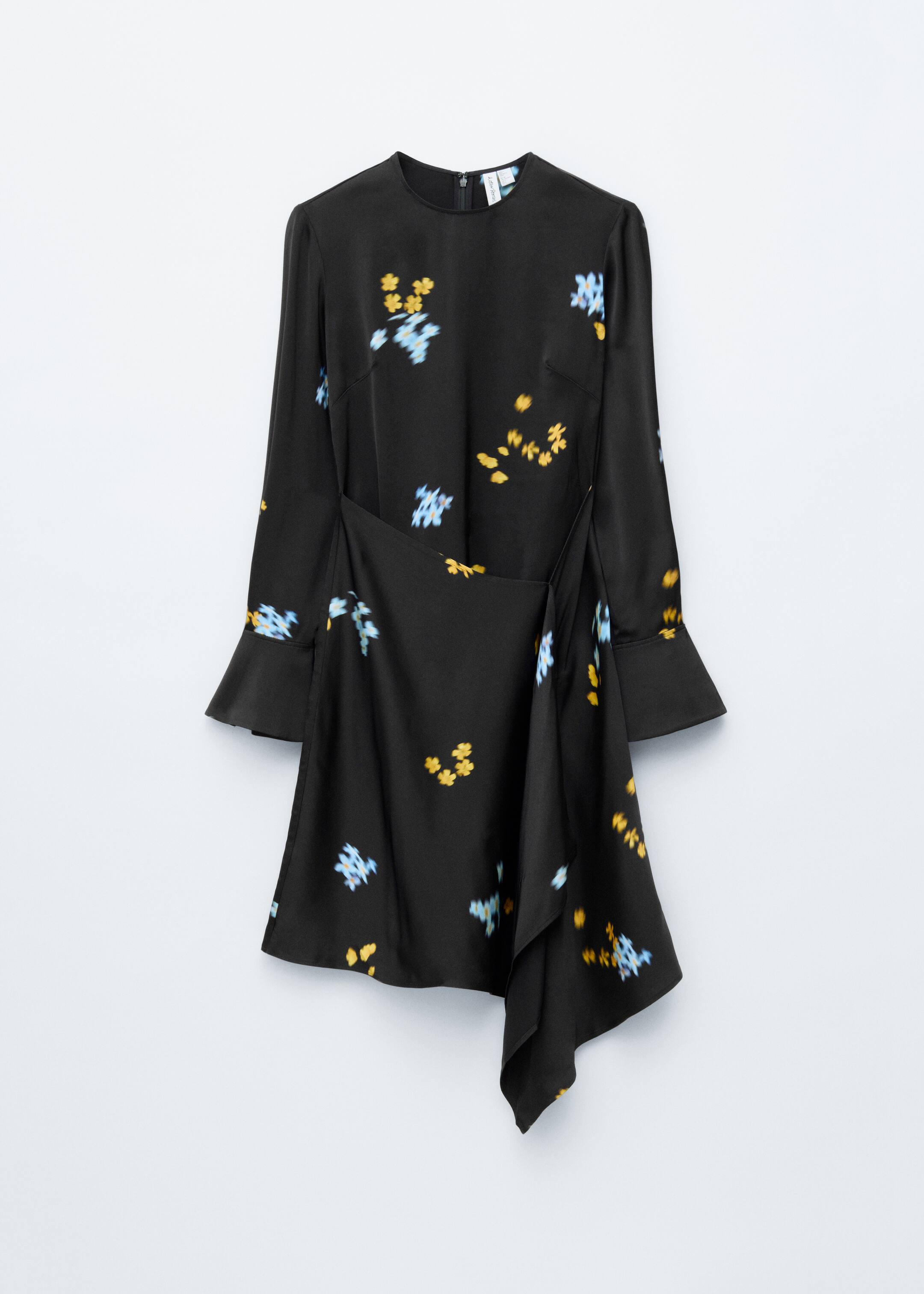 Agrandir l'image: Une robe noire présente un col rond, des manches longues avec des poignets évasés, et des motifs floraux jaunes et bleus dispersés, vue de face. Elle arbore un panneau avant superposé créant un ourlet asymétrique.