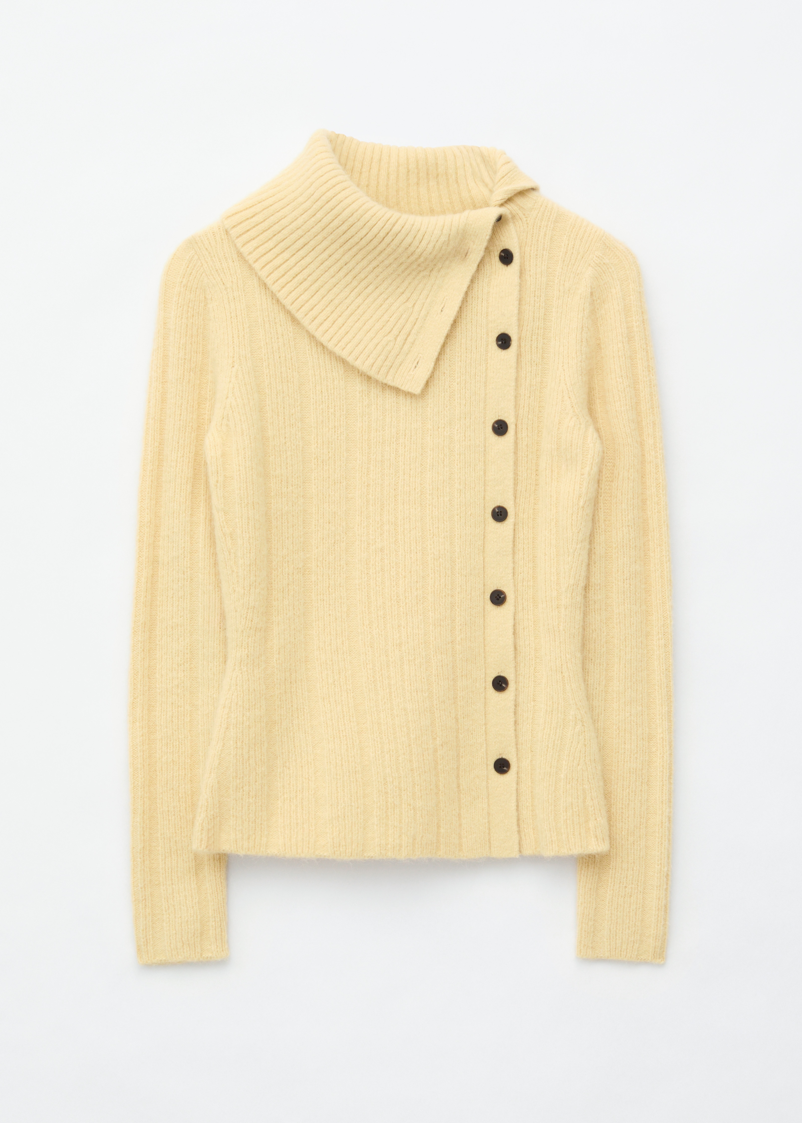 A light yellow fuzzy knit cardigan features an asymmetrical design, showcasing a high, cowl-like collar on the left side and a diagonal button fastening with dark buttons. It has long sleeves and a cropped, asymmetrical hem.