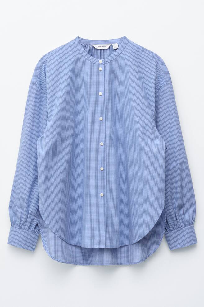 An oversized blue shirt with a subtle grid pattern is displayed from the FRONT, showcasing a band collar, a front button placket with white buttons, dropped shoulders, long sleeves with buttoned cuffs, and a rounded hem. - 1