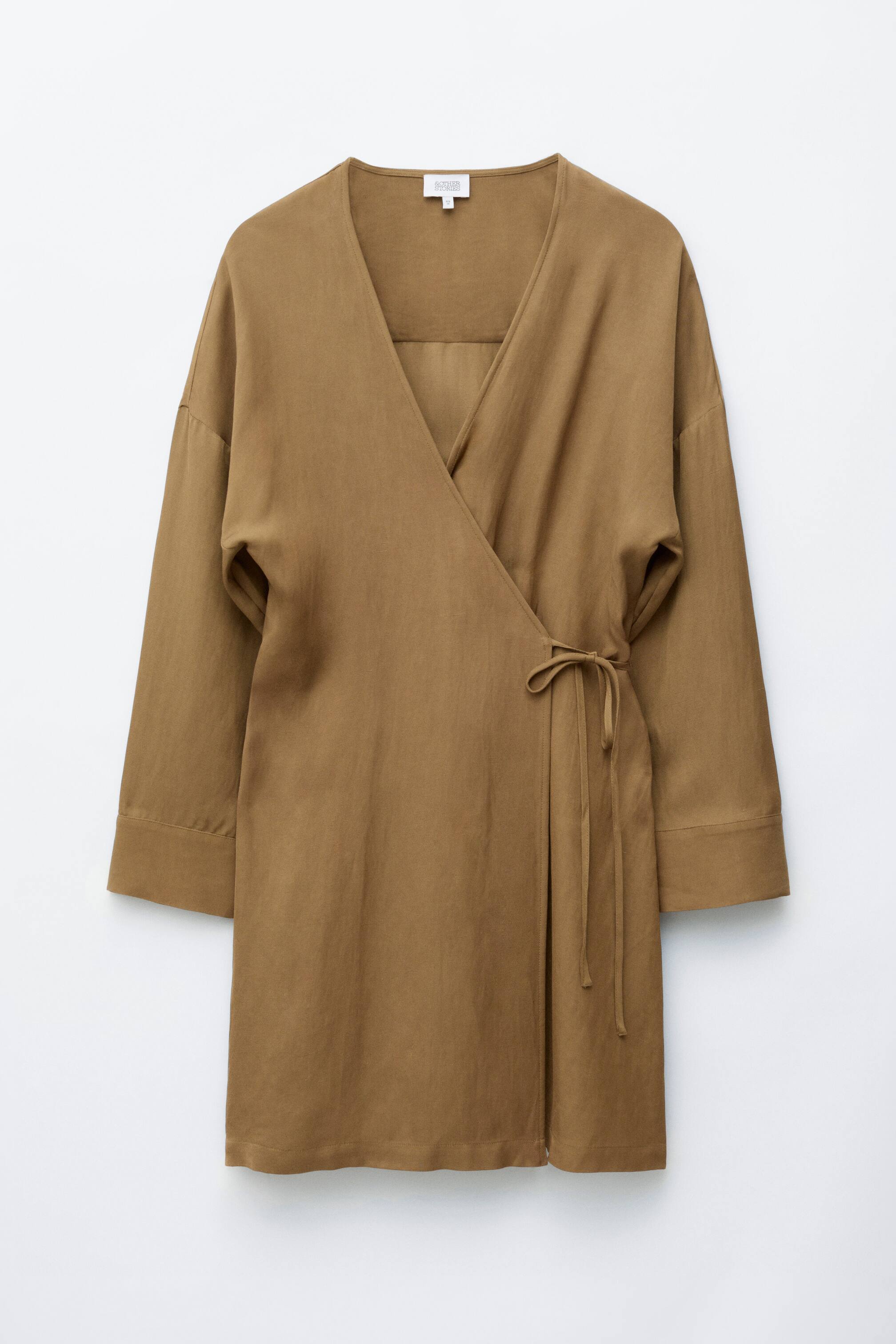 Agrandir l'image: Une robe portefeuille courte marron est présentée de face, avec un décolleté en V, des épaules tombantes et de longues manches à poignets. Une ceinture en tissu assorti resserre la taille sur le côté.