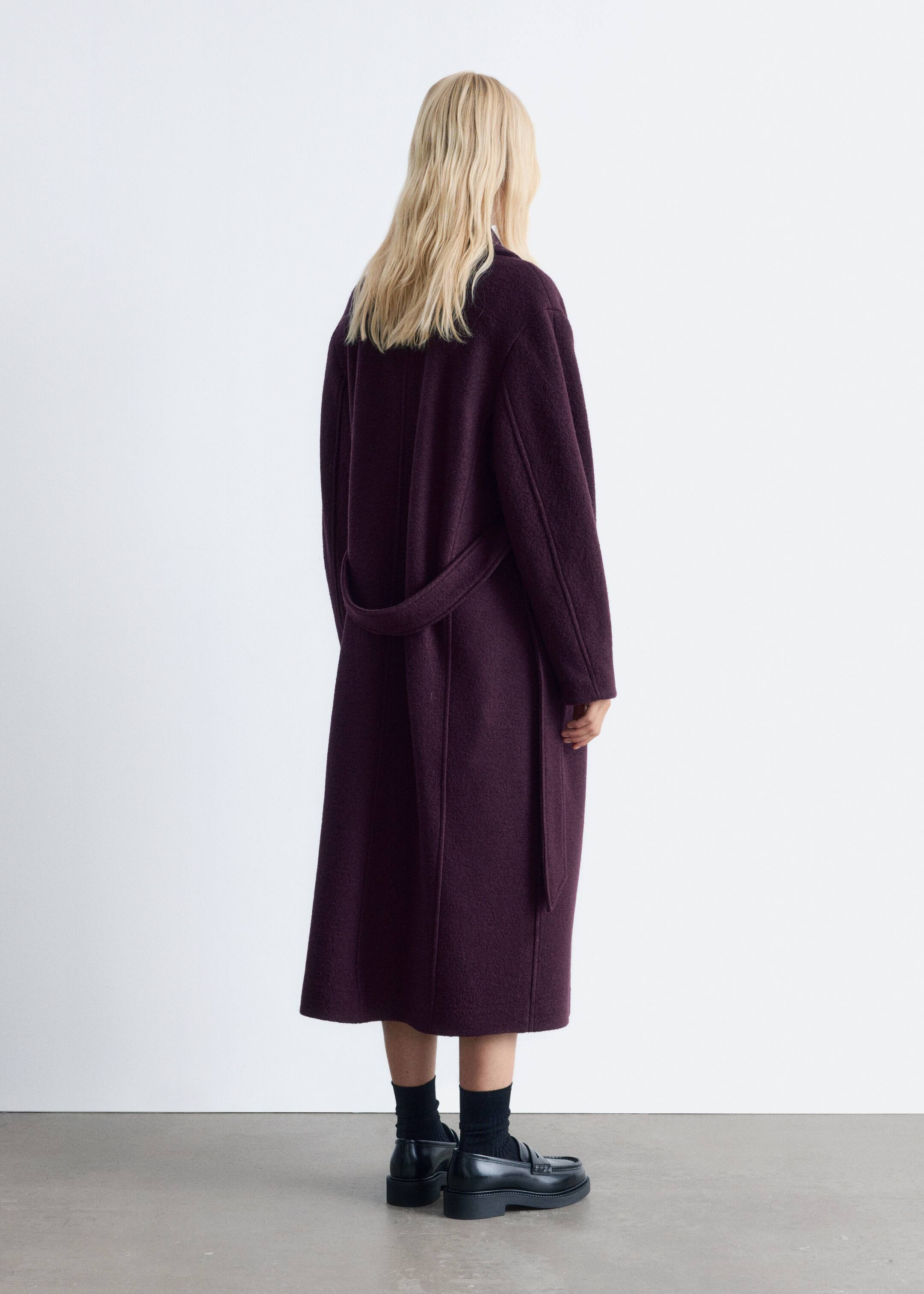 Agrandir l'image: Un manteau enveloppant violet foncé est présenté d'une vue arrière légèrement inclinée. Il présente une silhouette longue et décontractée dans un tissu texturé, avec une ceinture en tissu assorti qui serre la taille.